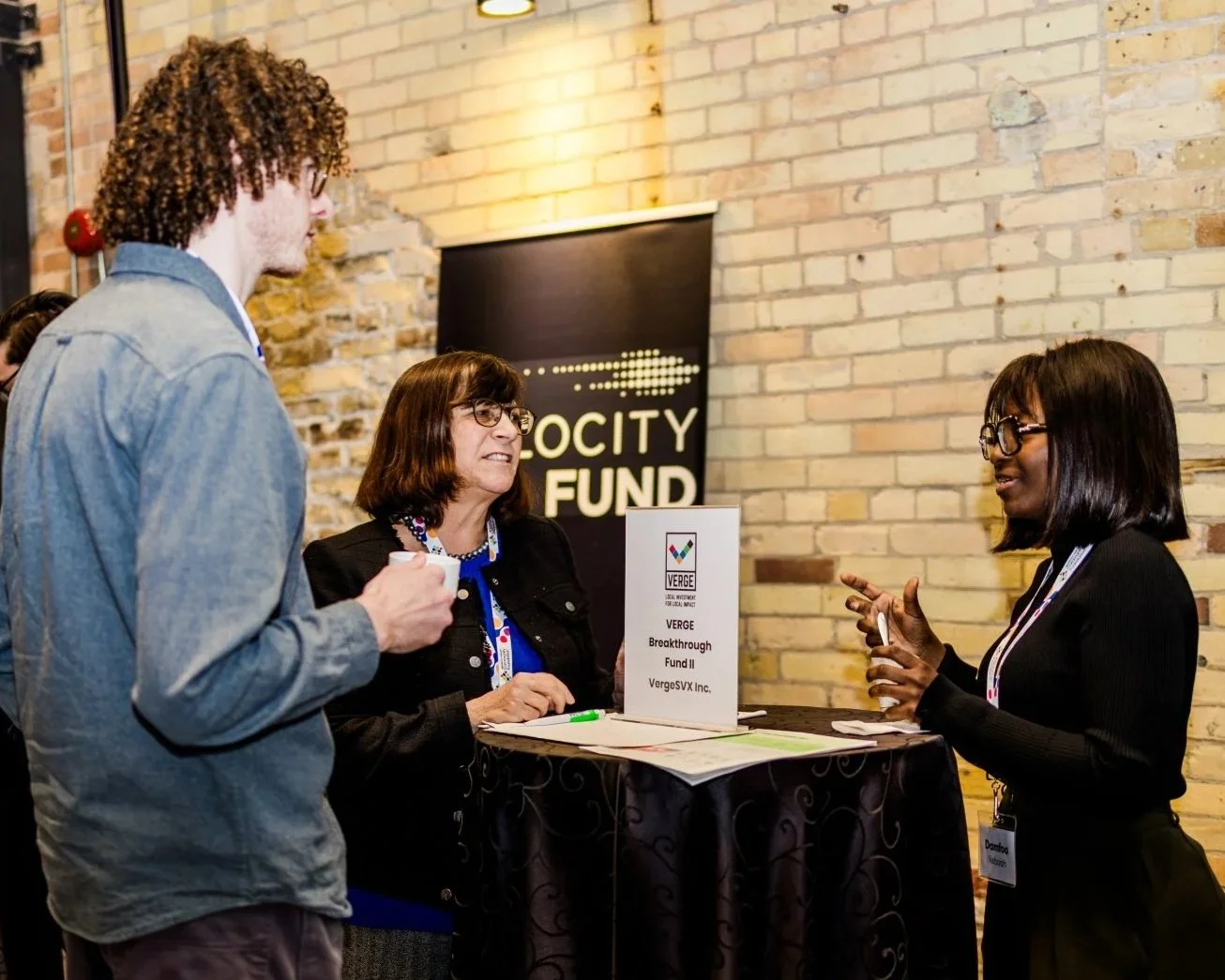 VERGE Breakthrough Fund II table at Impact Fund Forum. Fund representative talking with guests