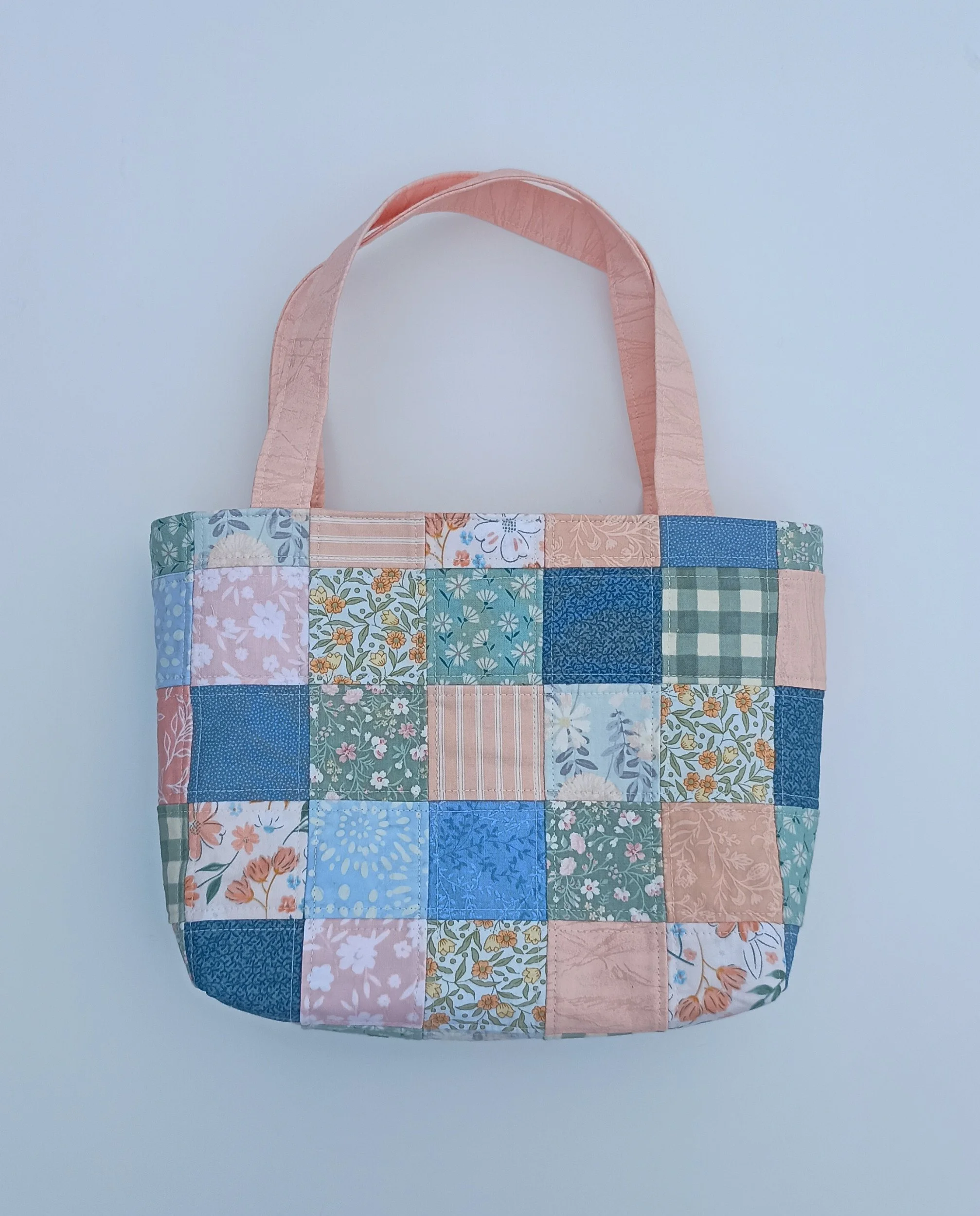 A quilted patchwork Bible Bag made from peach, green, and blue fabrics