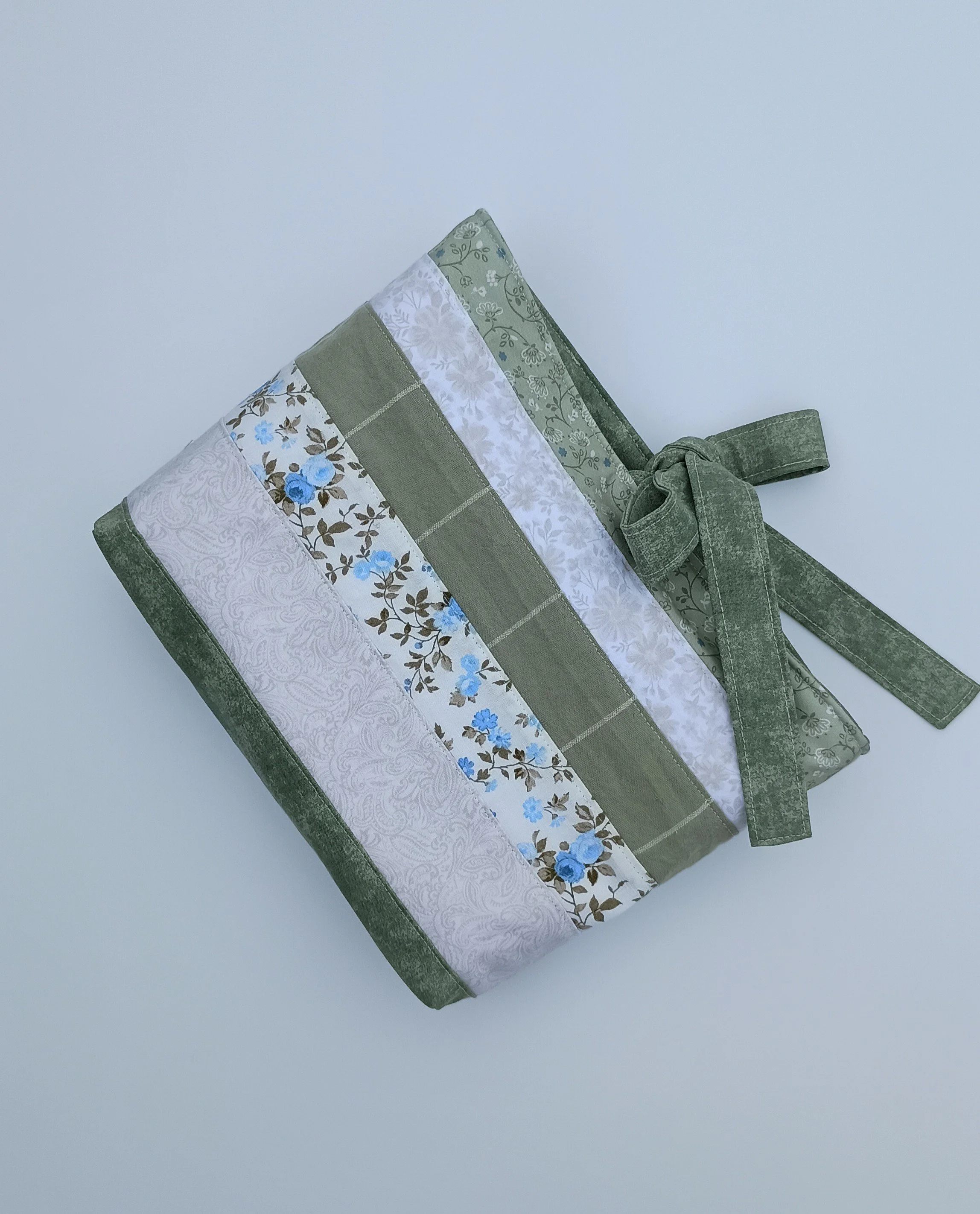 A quilted Bible Sleeve made from sage, blue, and beige fabrics
