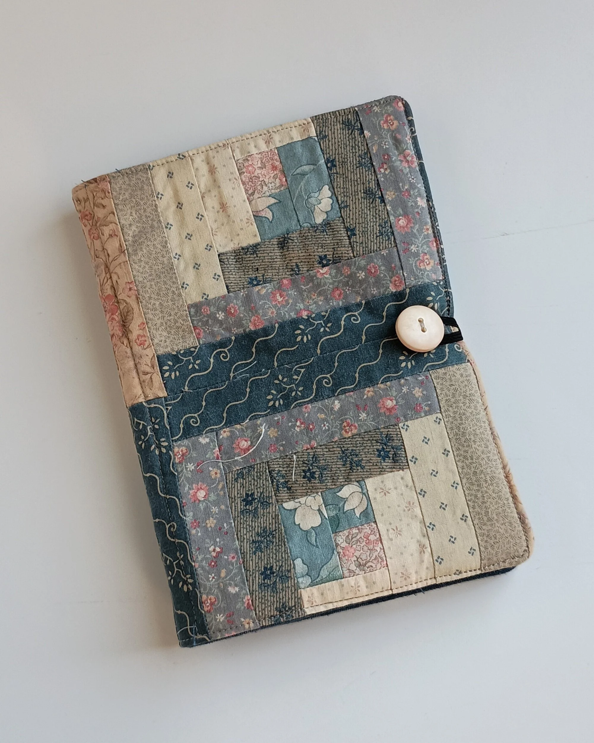 A notepad cover with a button closure made from a vintage log cabin quilt top