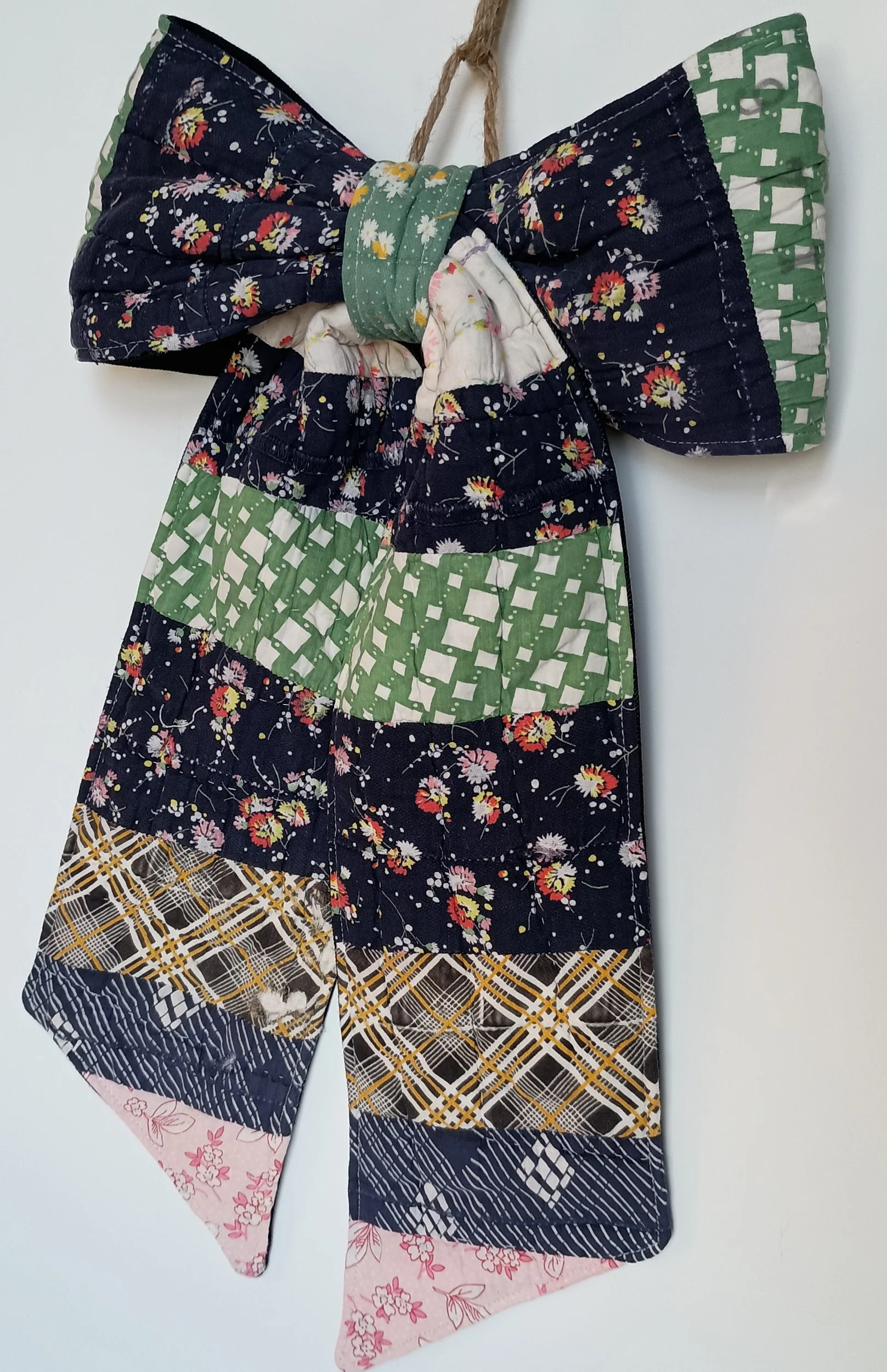A decorative bow made from an antique patchwork, with navy being the dominant color