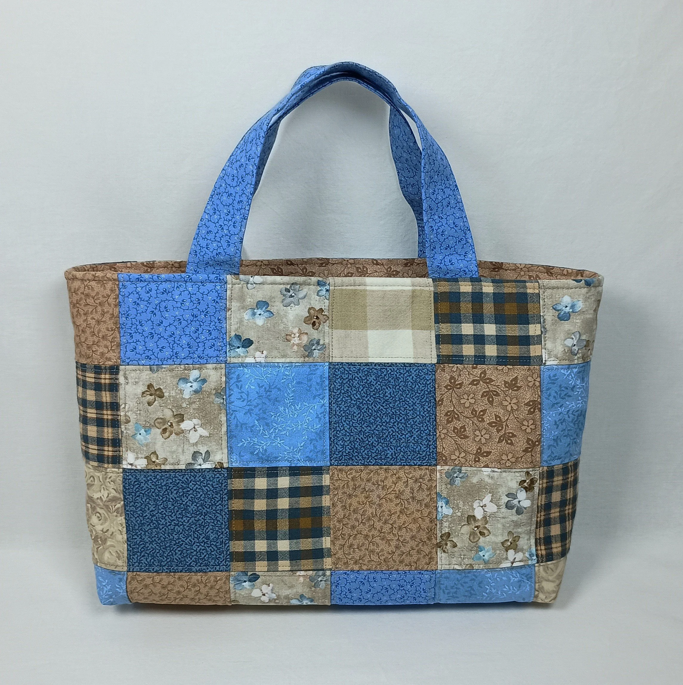 A Bible tote bag made from patchwork fabric squares in coordinating blues and browns