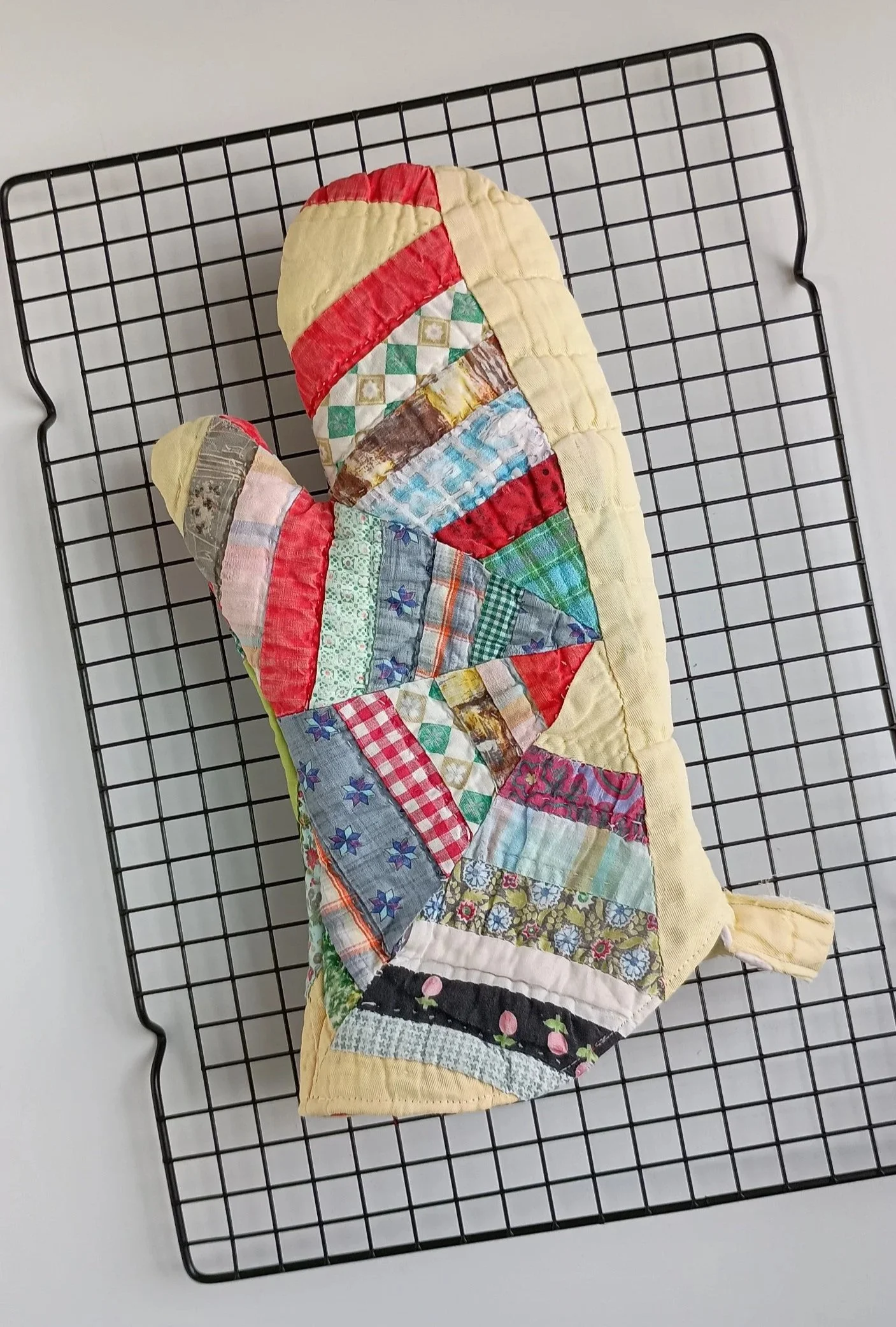 An oven mitt made from a brightly colored antique quilt