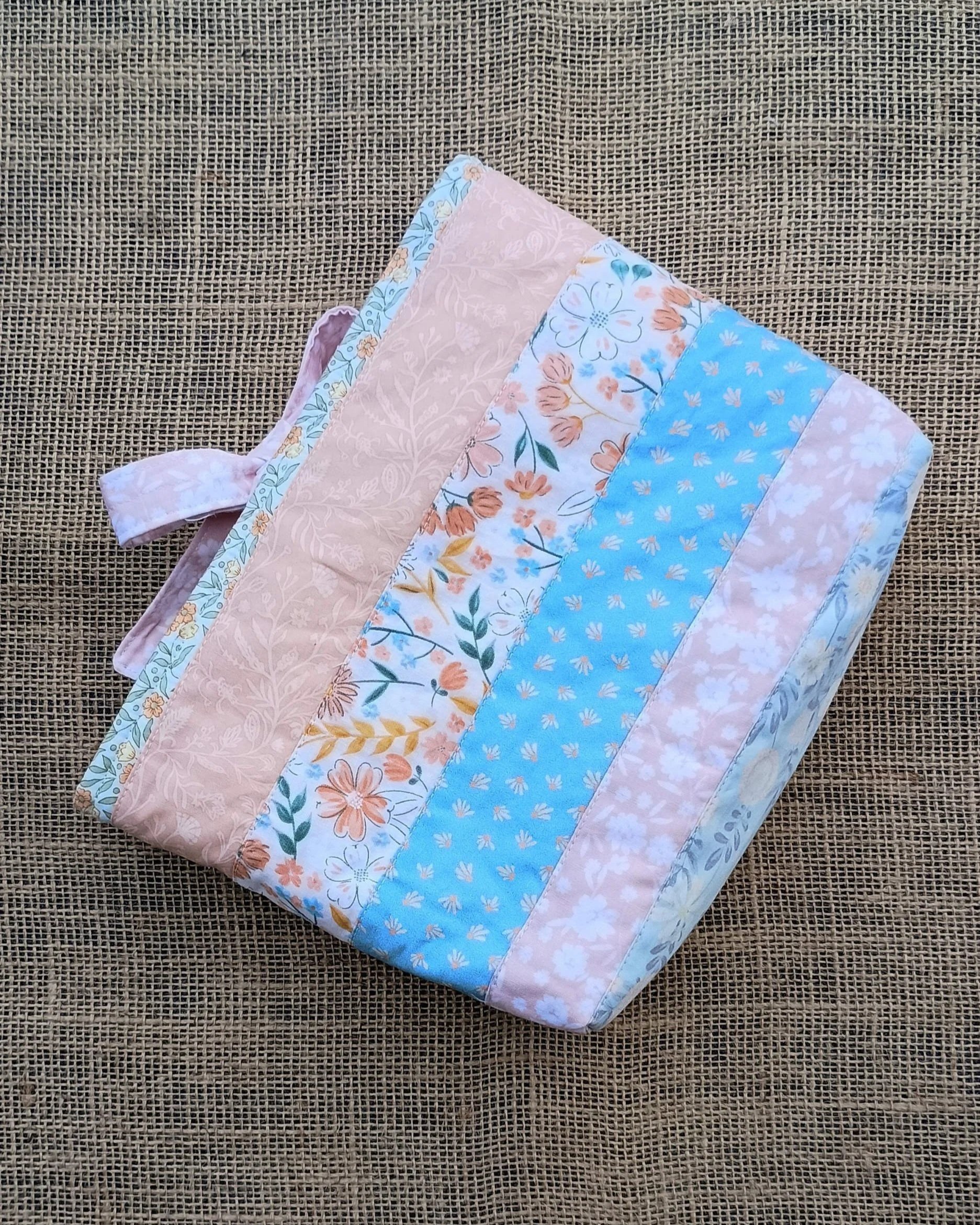 A quilted Bible Sleeve made from peach, green, and blue floral fabrics