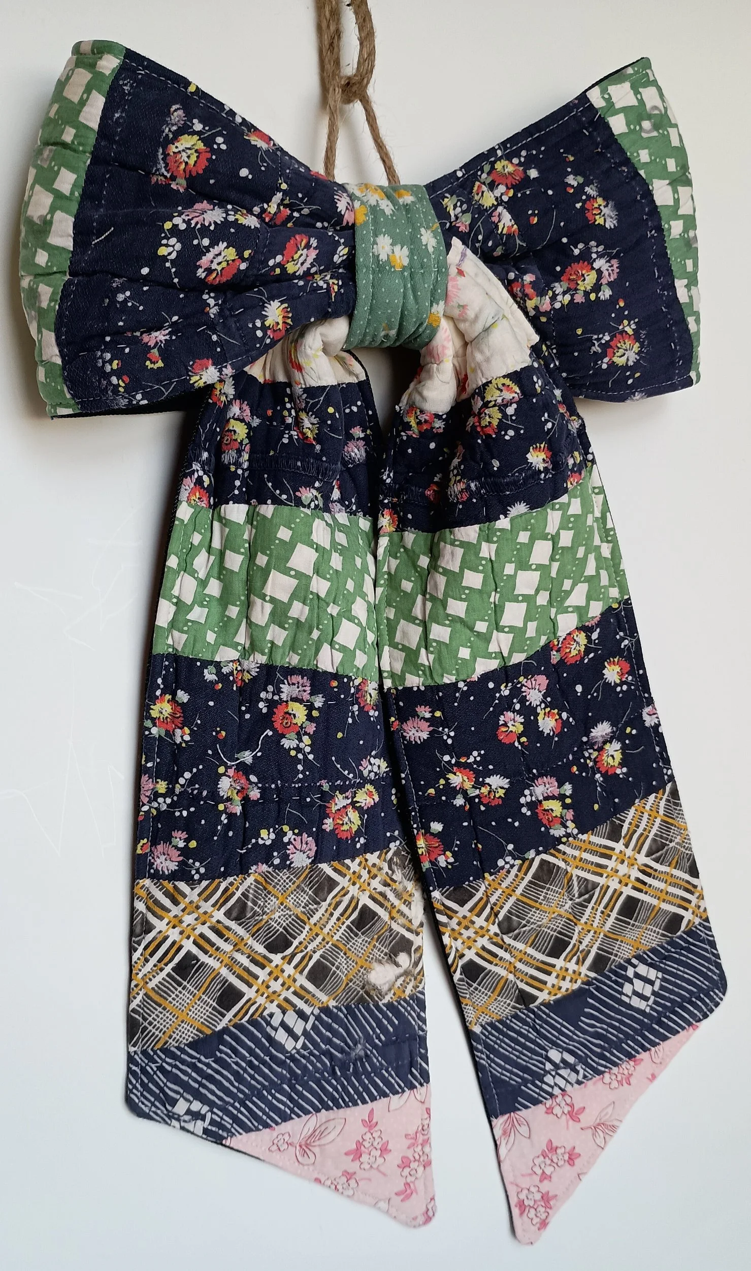 A decorative bow made from an antique patchwork, with navy being the dominant color