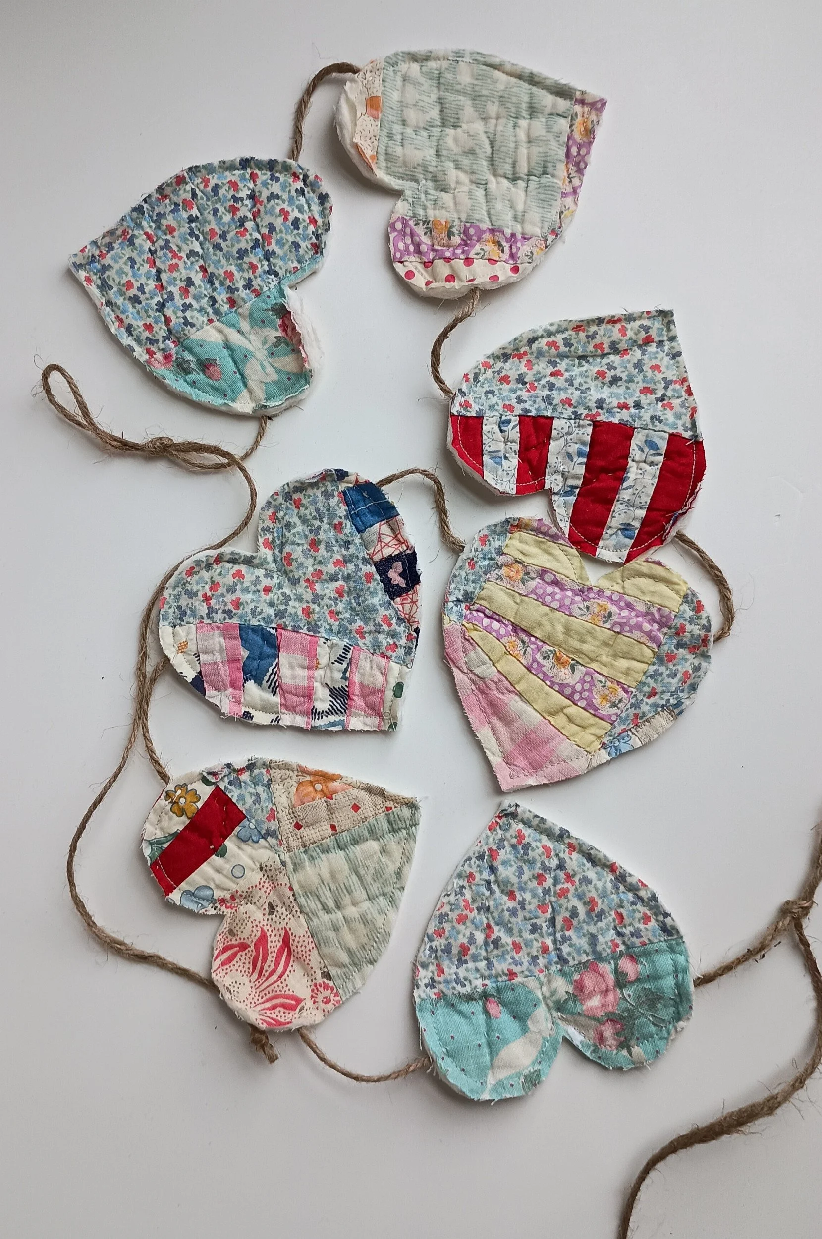 A decorative garland with hearts cut from an antique quilt attatched to jute rope