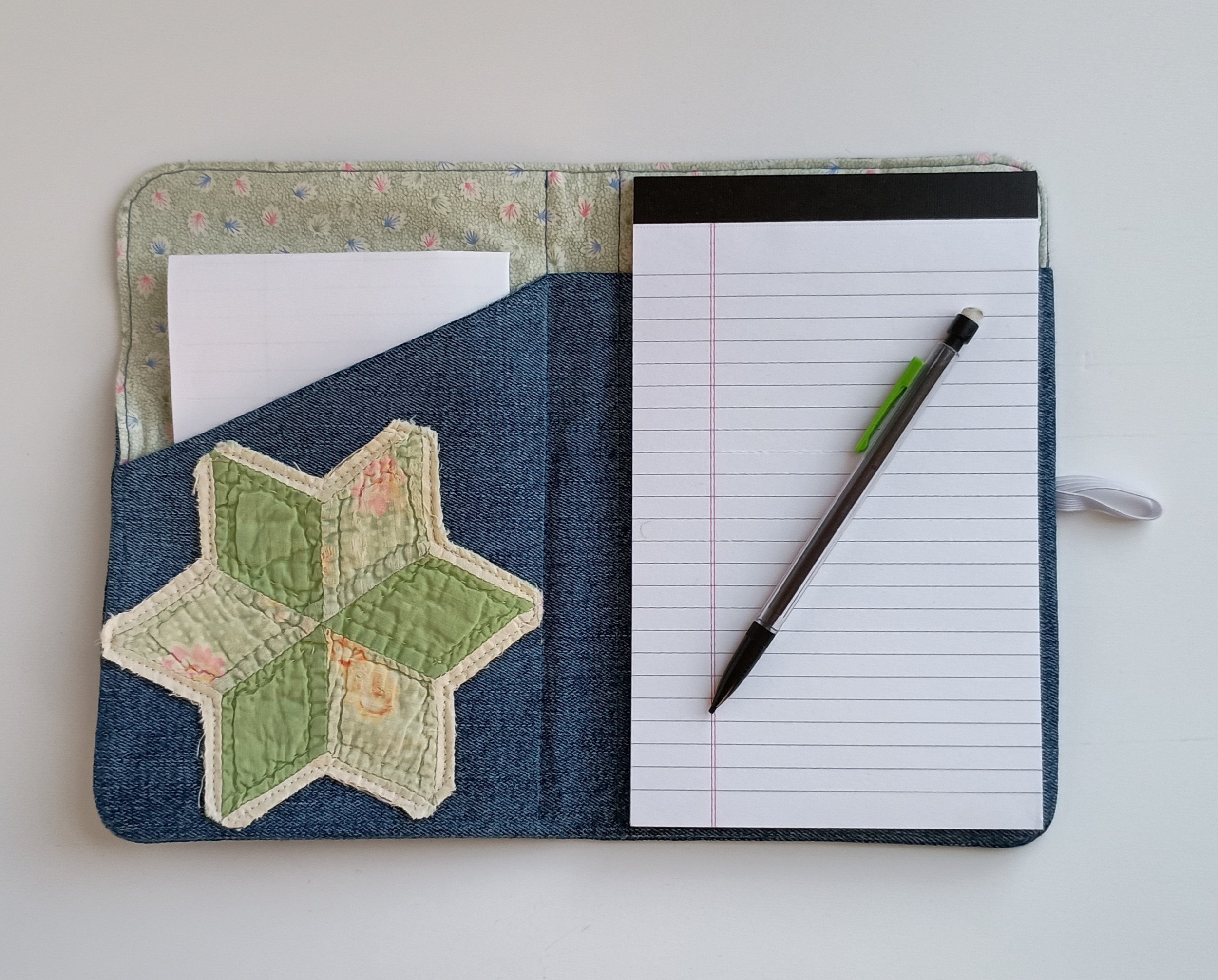 The inside of a notepad cover made from denim fabric with an antique quilt star appliqued to one side