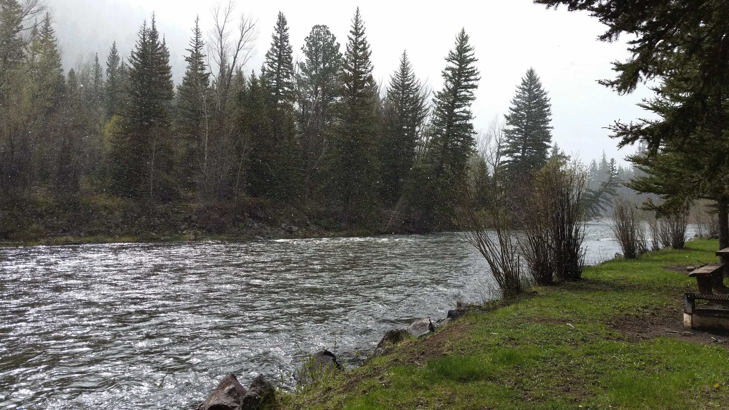 A river flowing in the mountains with snow falling