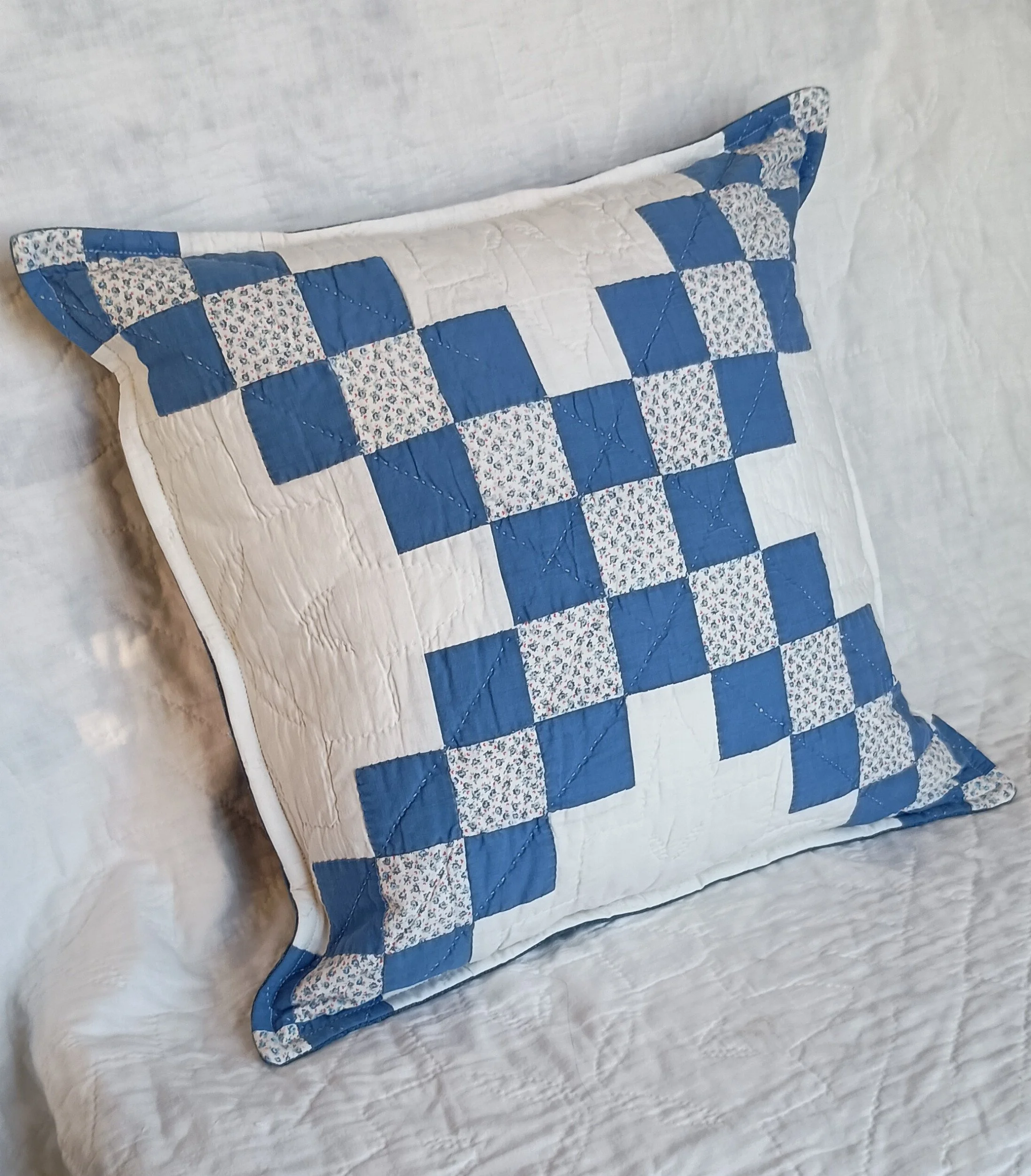 A decorative pillow made from a blue and white patchwork quilt