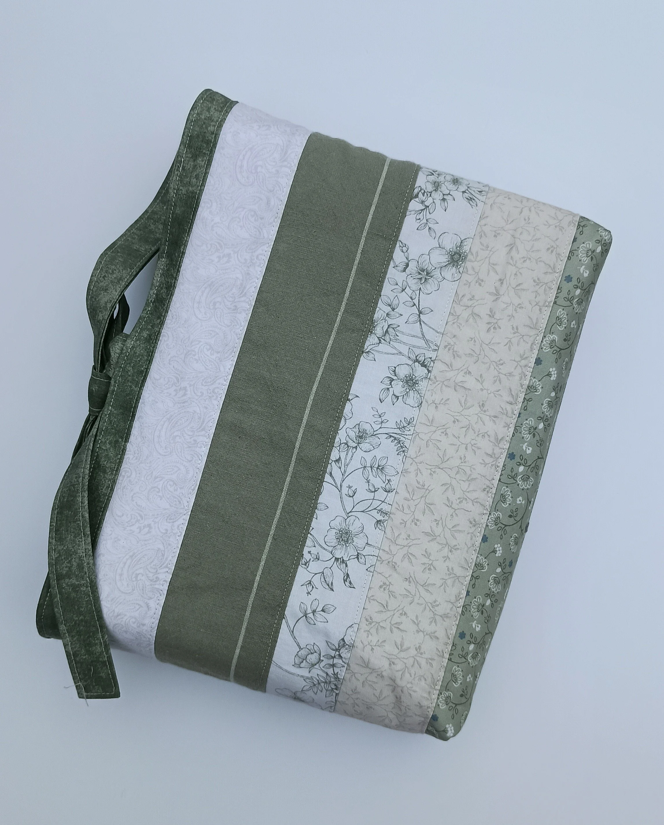 A quilted Bible Sleeve made from sage, blue, and beige fabrics