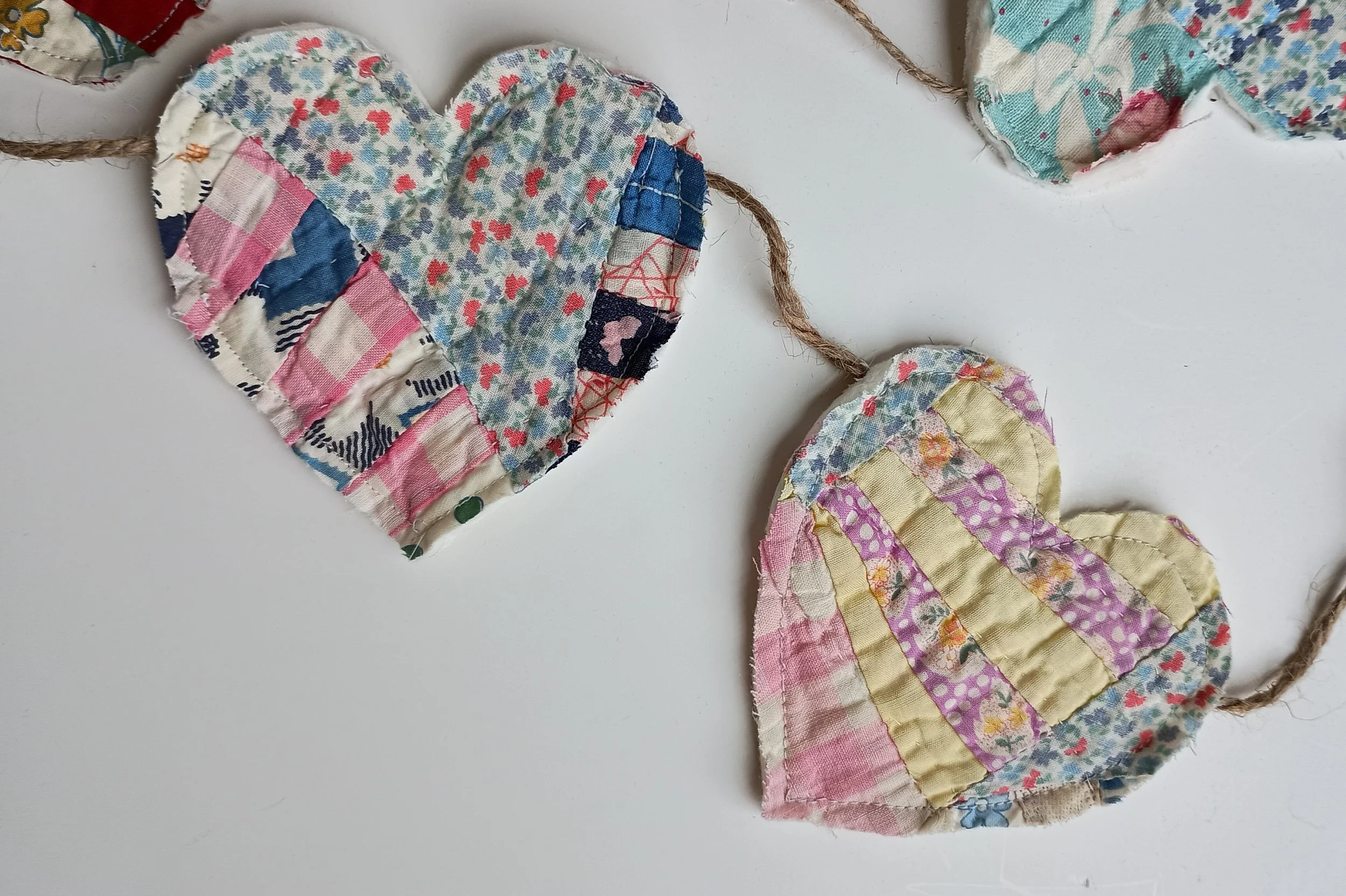 A decorative garland with hearts cut from an antique quilt attatched to jute rope