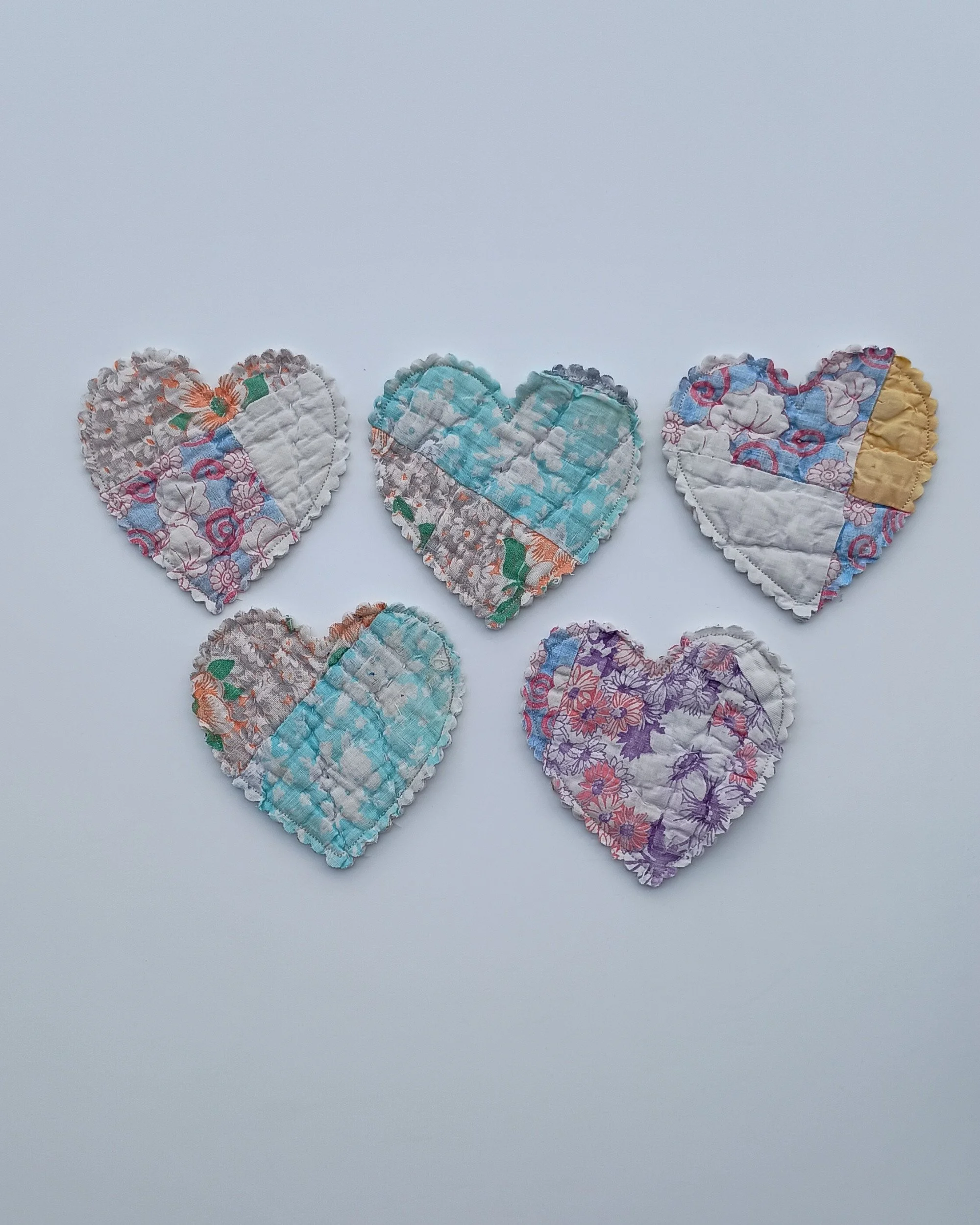 A set of 5 heart shapes cut out of a pastel antique quilt