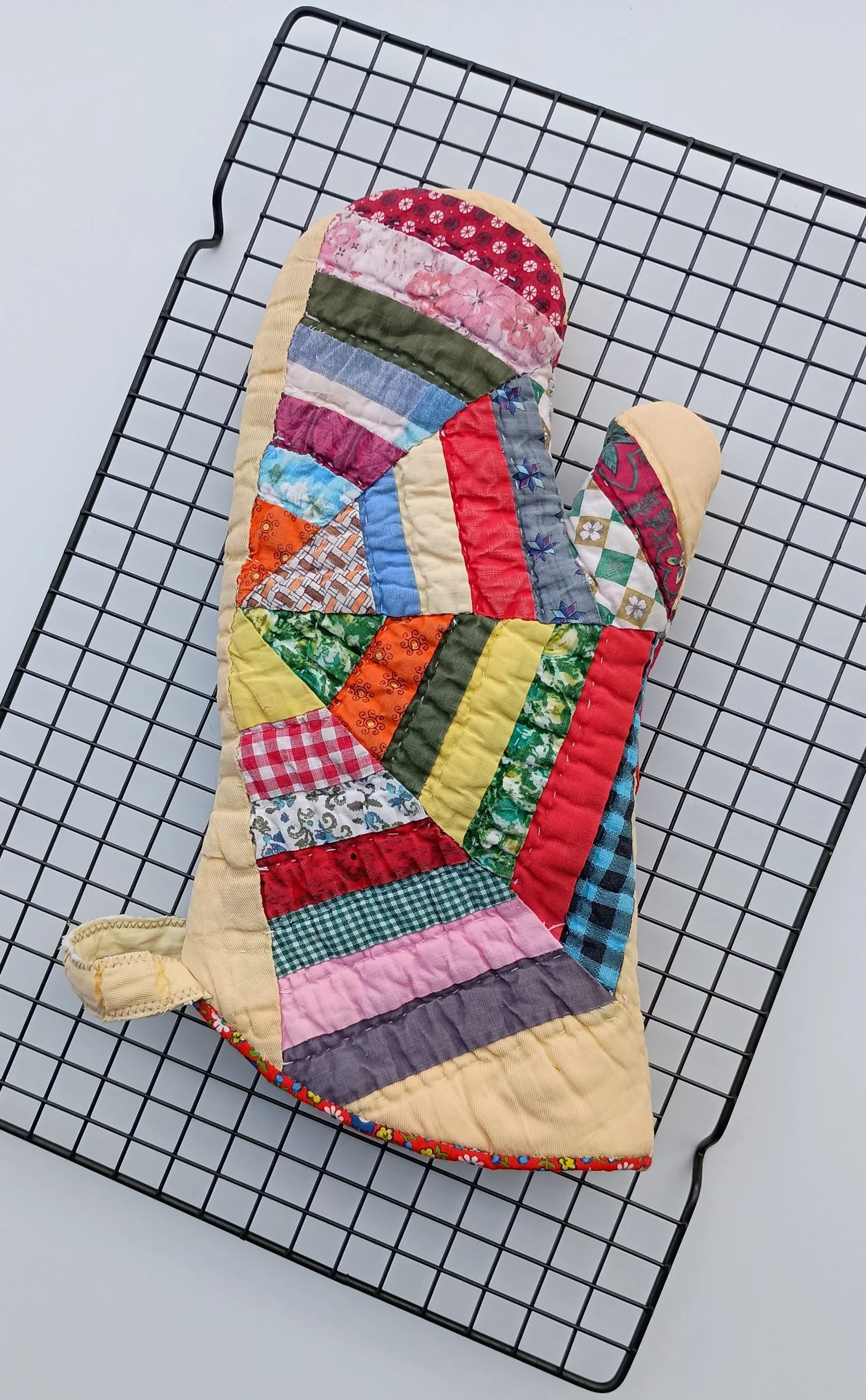 An oven mitt made from a brightly colored antique quilt