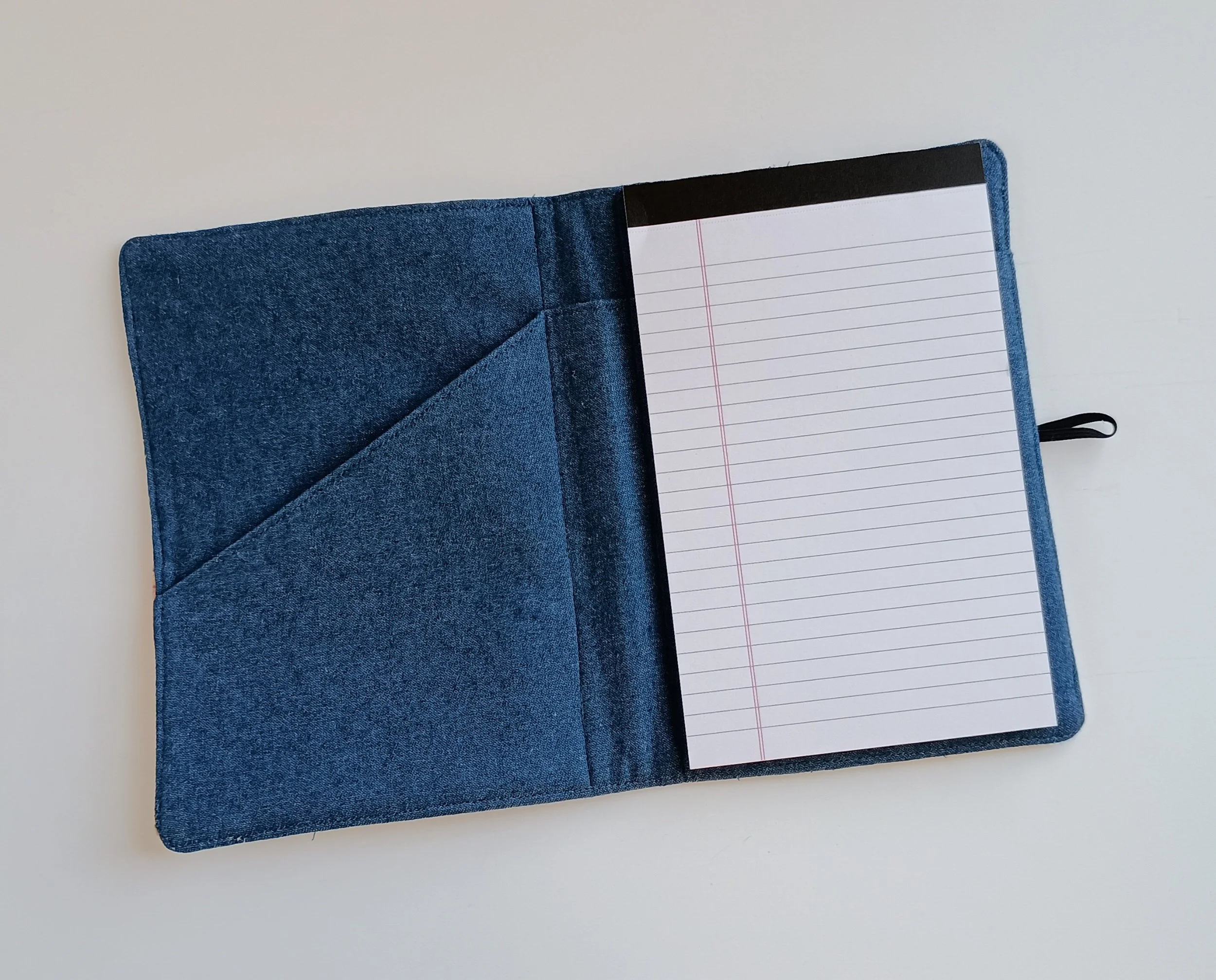 The inside of a notepad cover made with denim fabric with a notepad and pocket