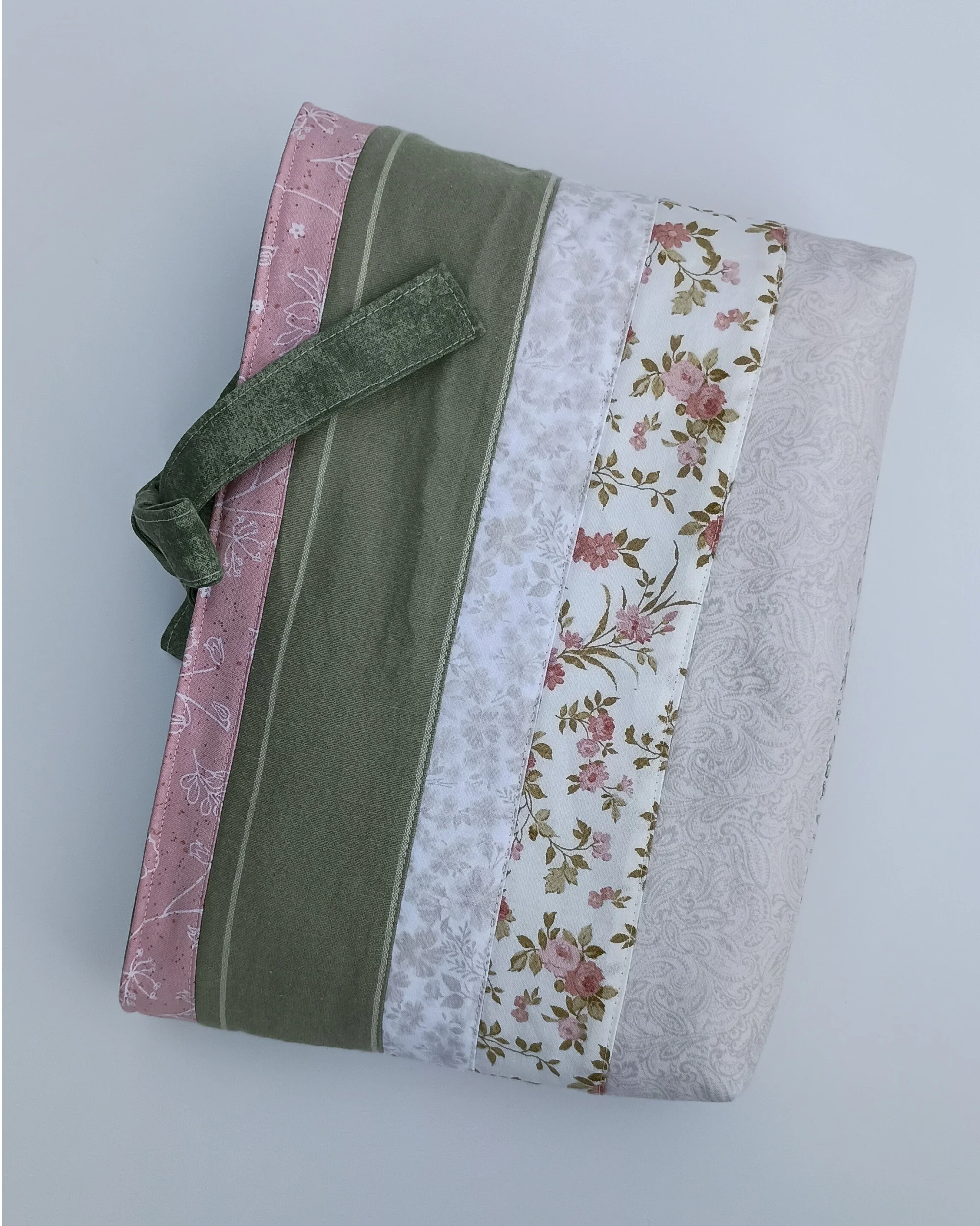 A quilted Bible Sleeve made from sage, pink, and beige fabrics