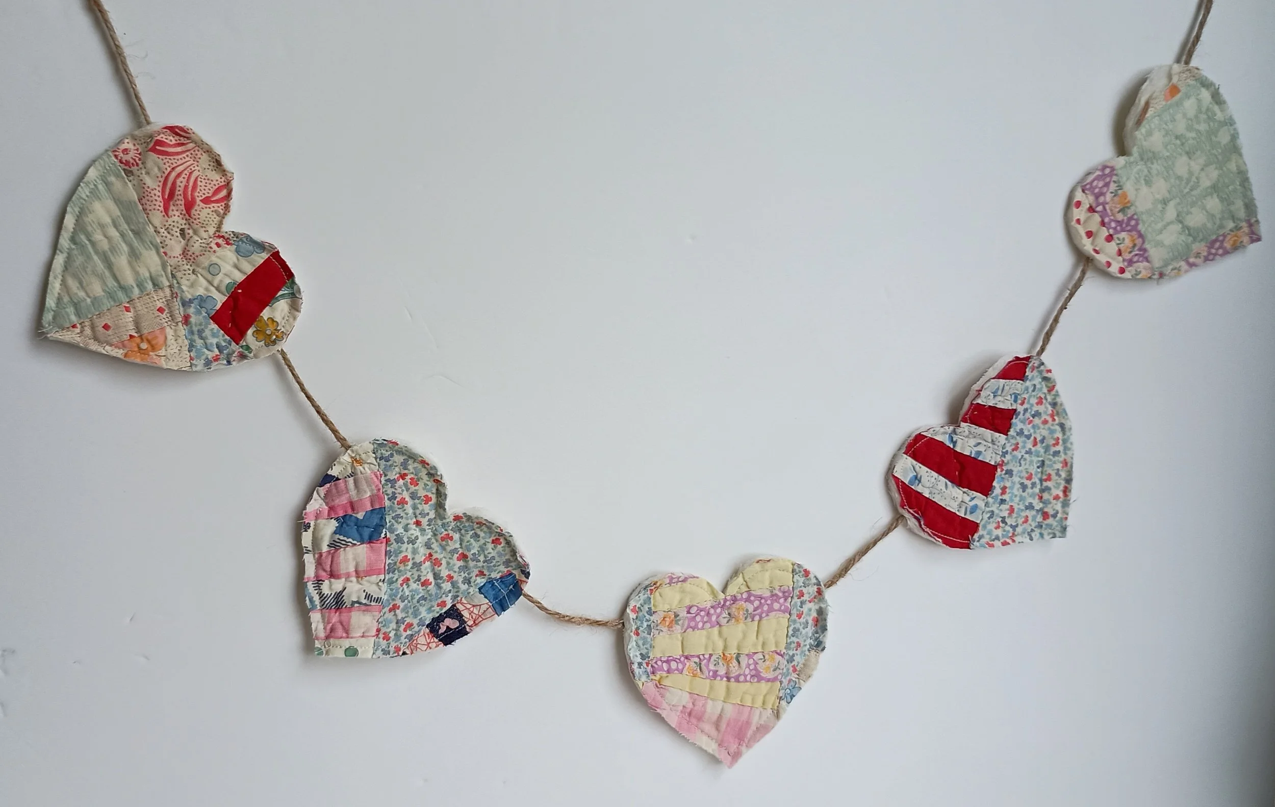 A decorative garland with hearts cut from an antique quilt attatched to jute rope