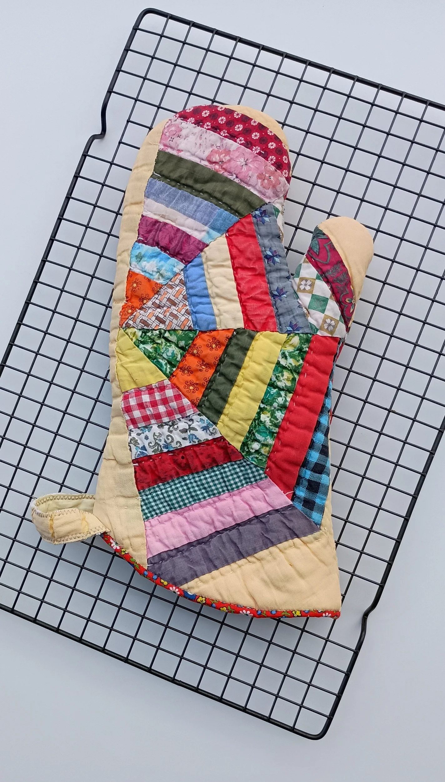 An oven mitt made from a brightly colored antique quilt