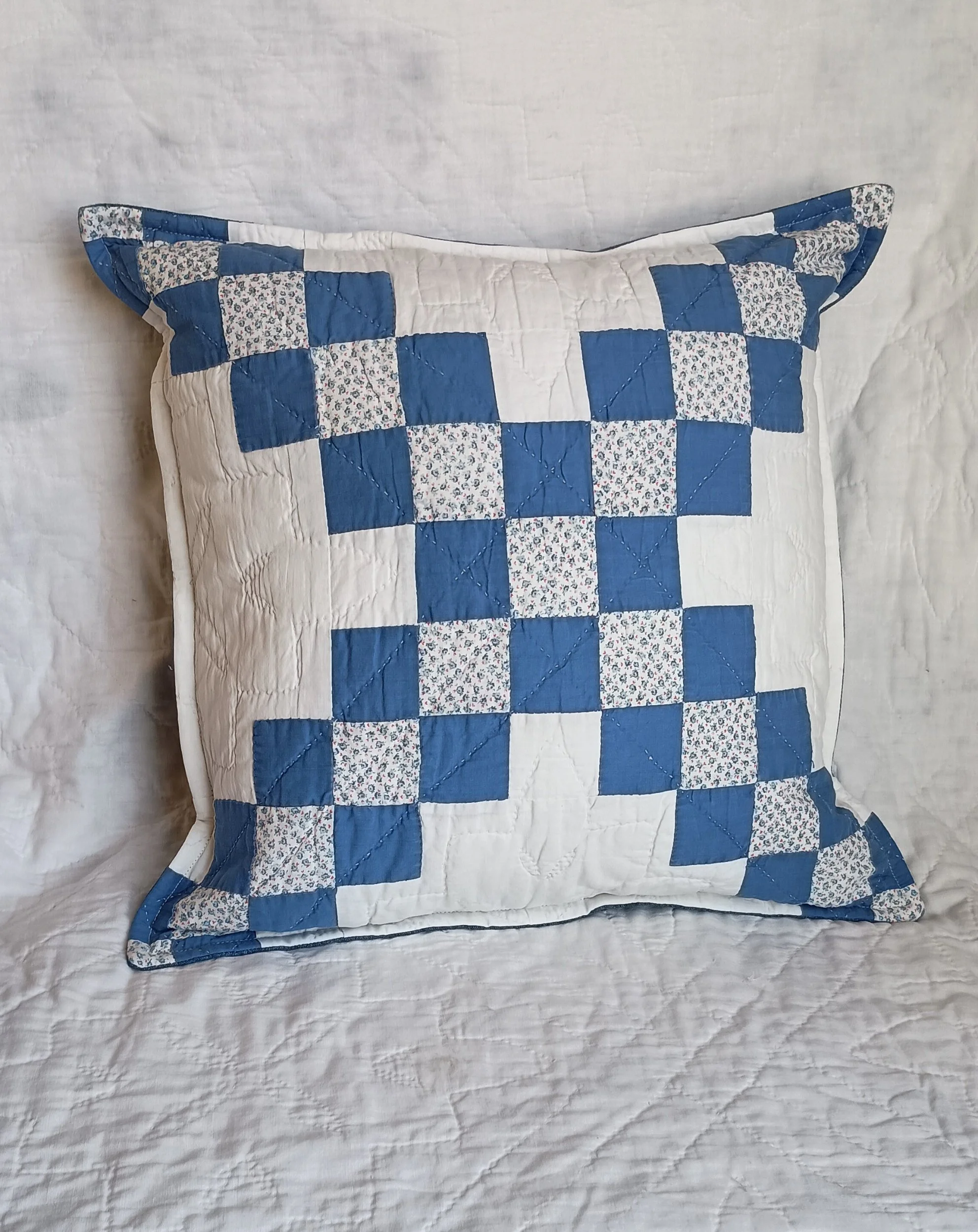 A decorative pillow made from a blue and white patchwork quilt