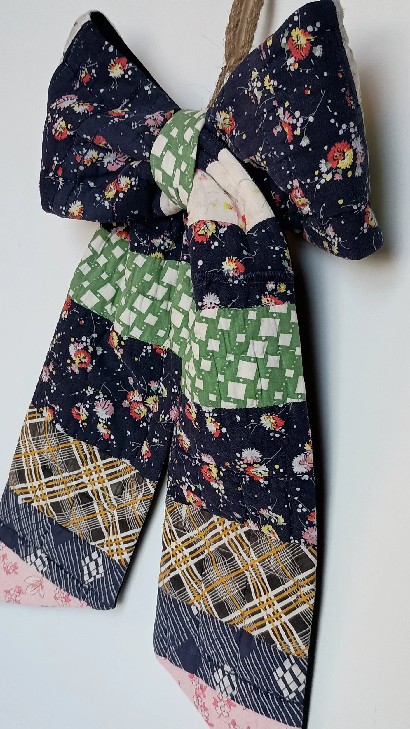 A decorative bow made from an antique patchwork, with navy being the dominant color