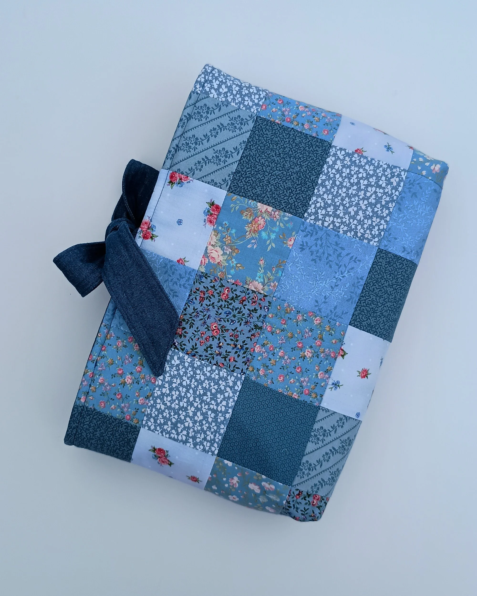 A quilted Bible Sleeve made from blue fabrics in a patchwork style