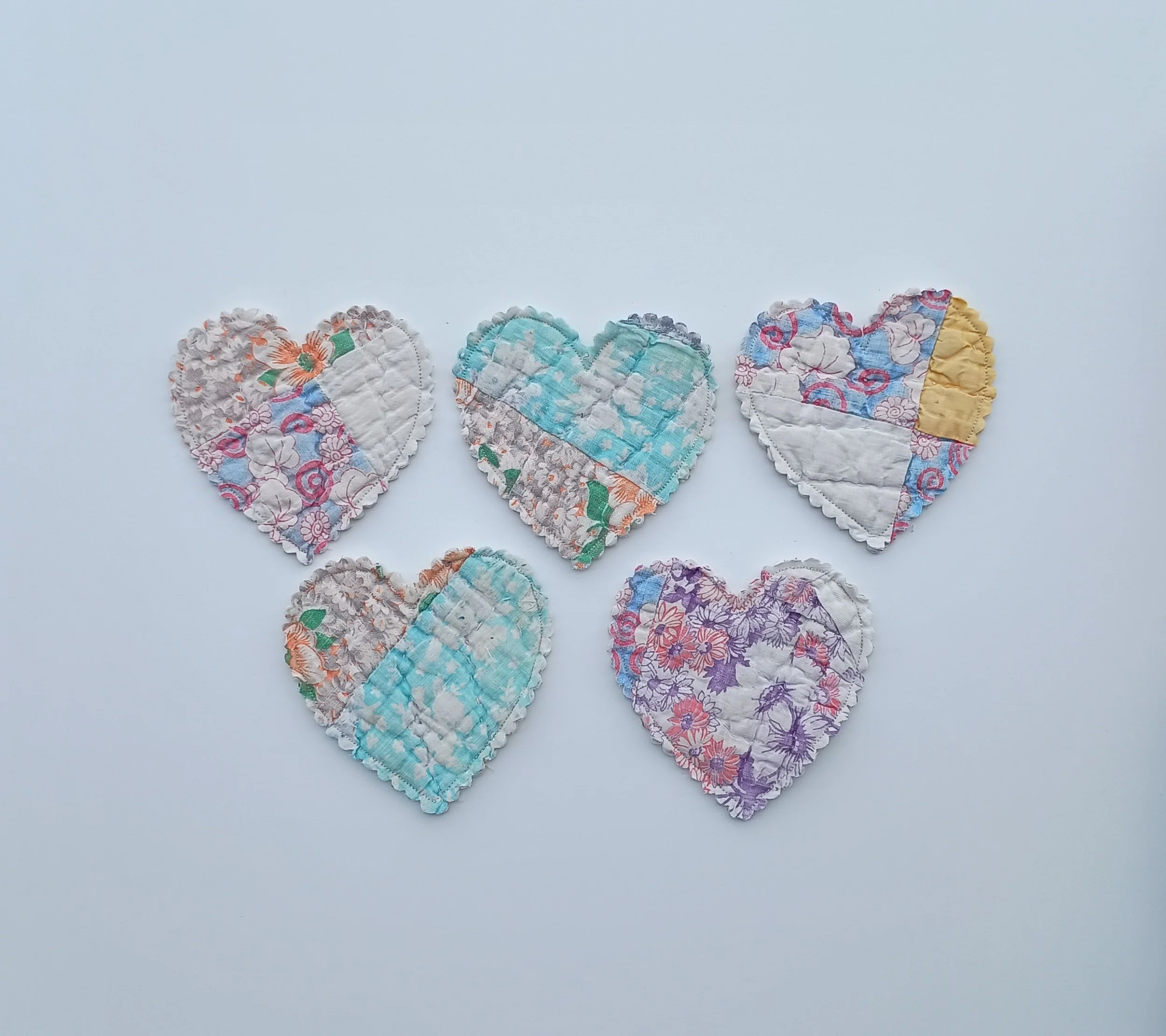 A set of 5 heart shapes cut out of a pastel antique quilt
