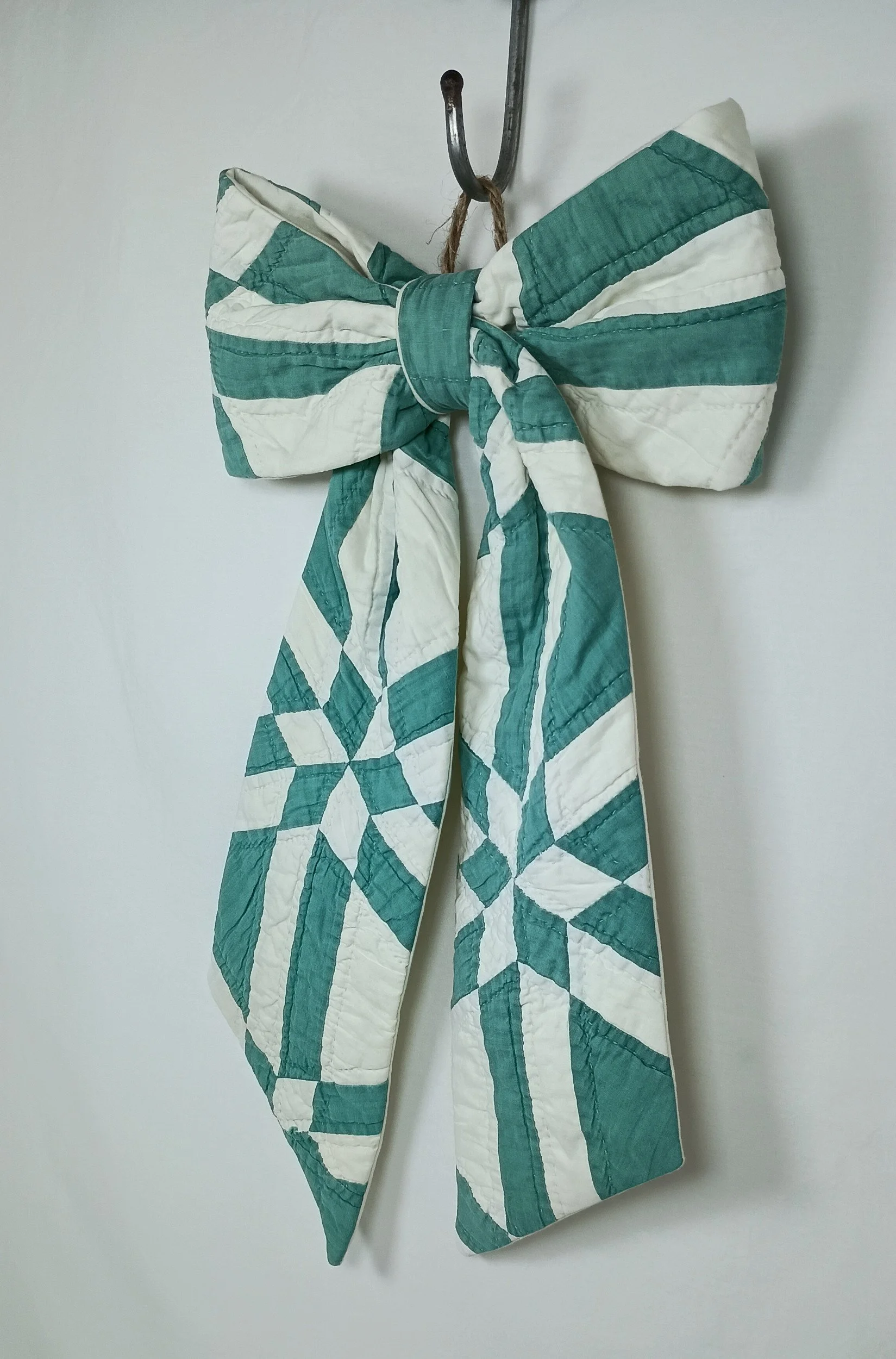 A green and white decorative bow made from an antique quilt