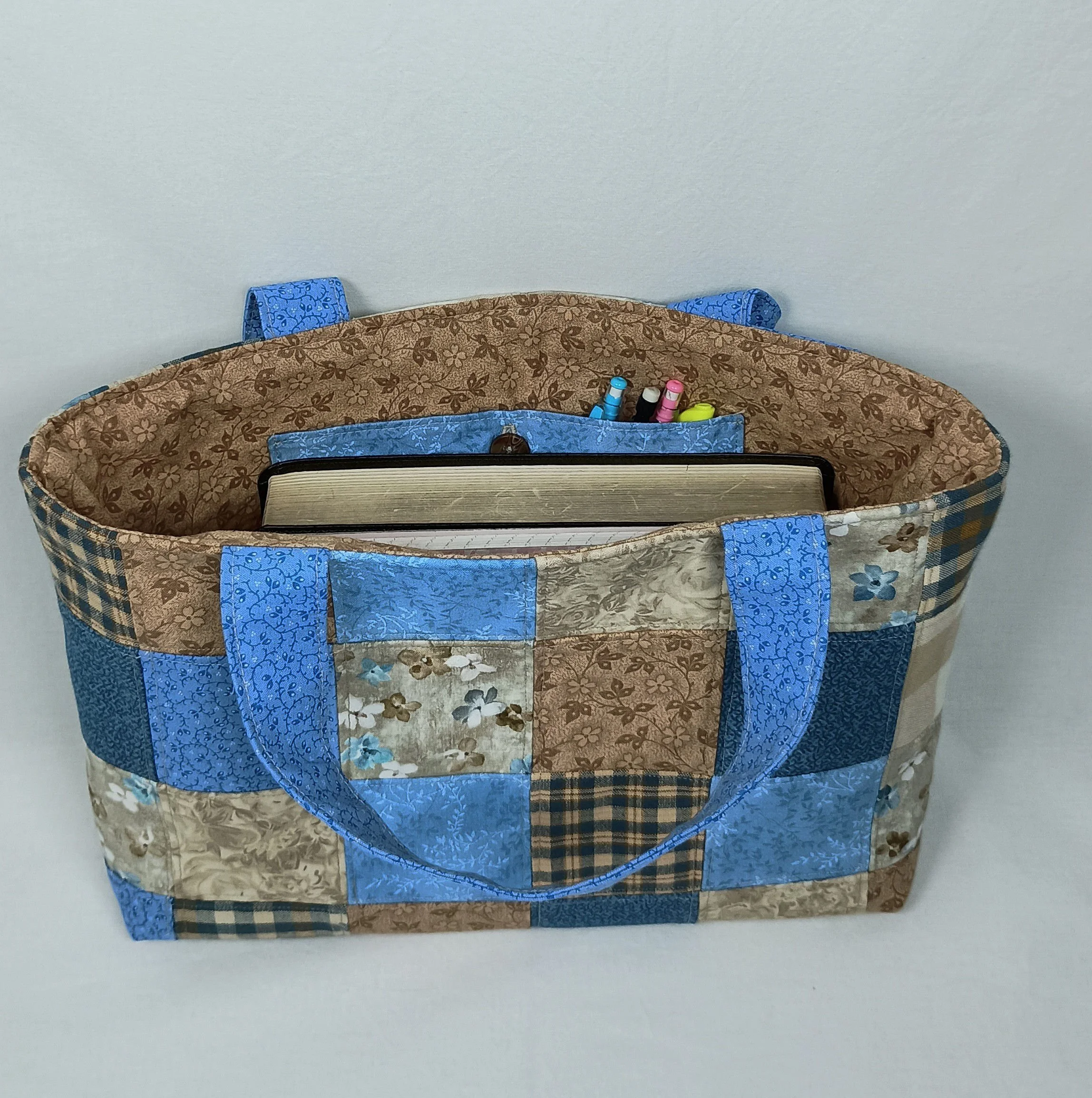 A Bible tote bag made from patchwork fabric squares in coordinating blues and browns