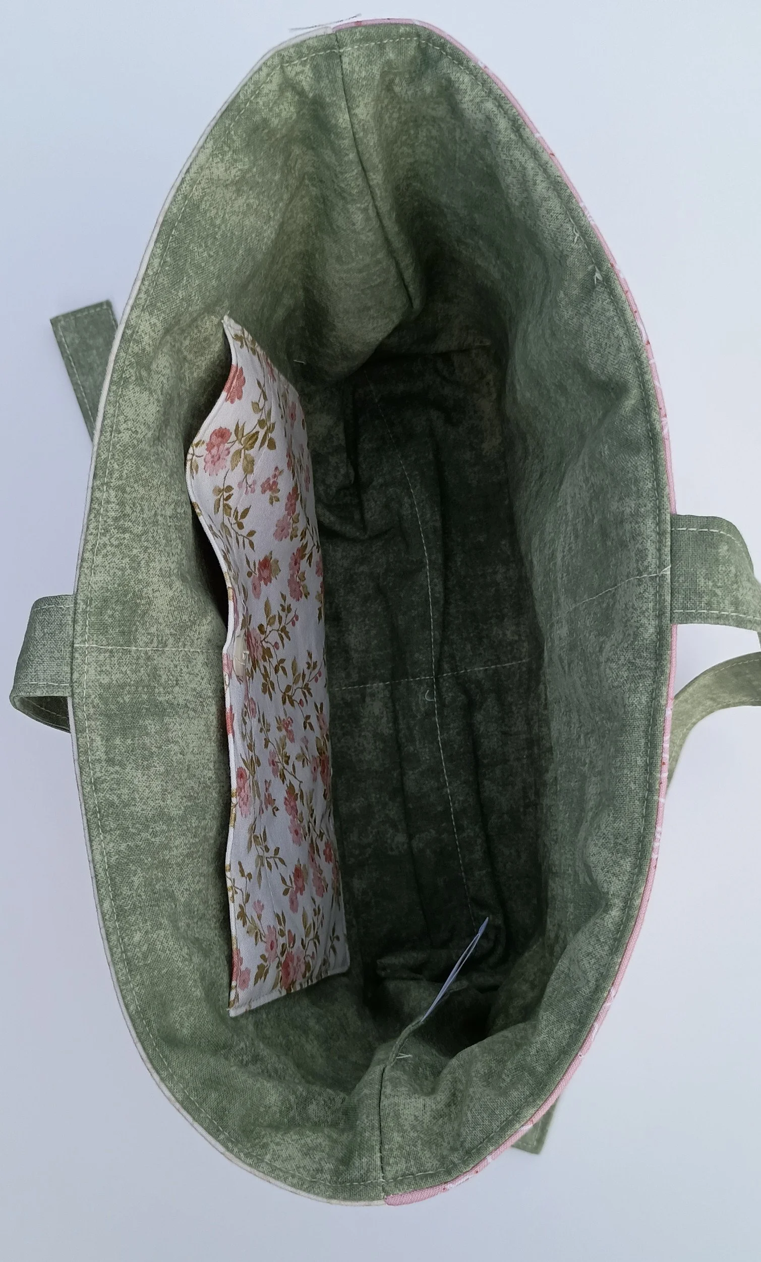 An inside view of a quilted Bible Sleeve made from sage, pink, and beige fabrics