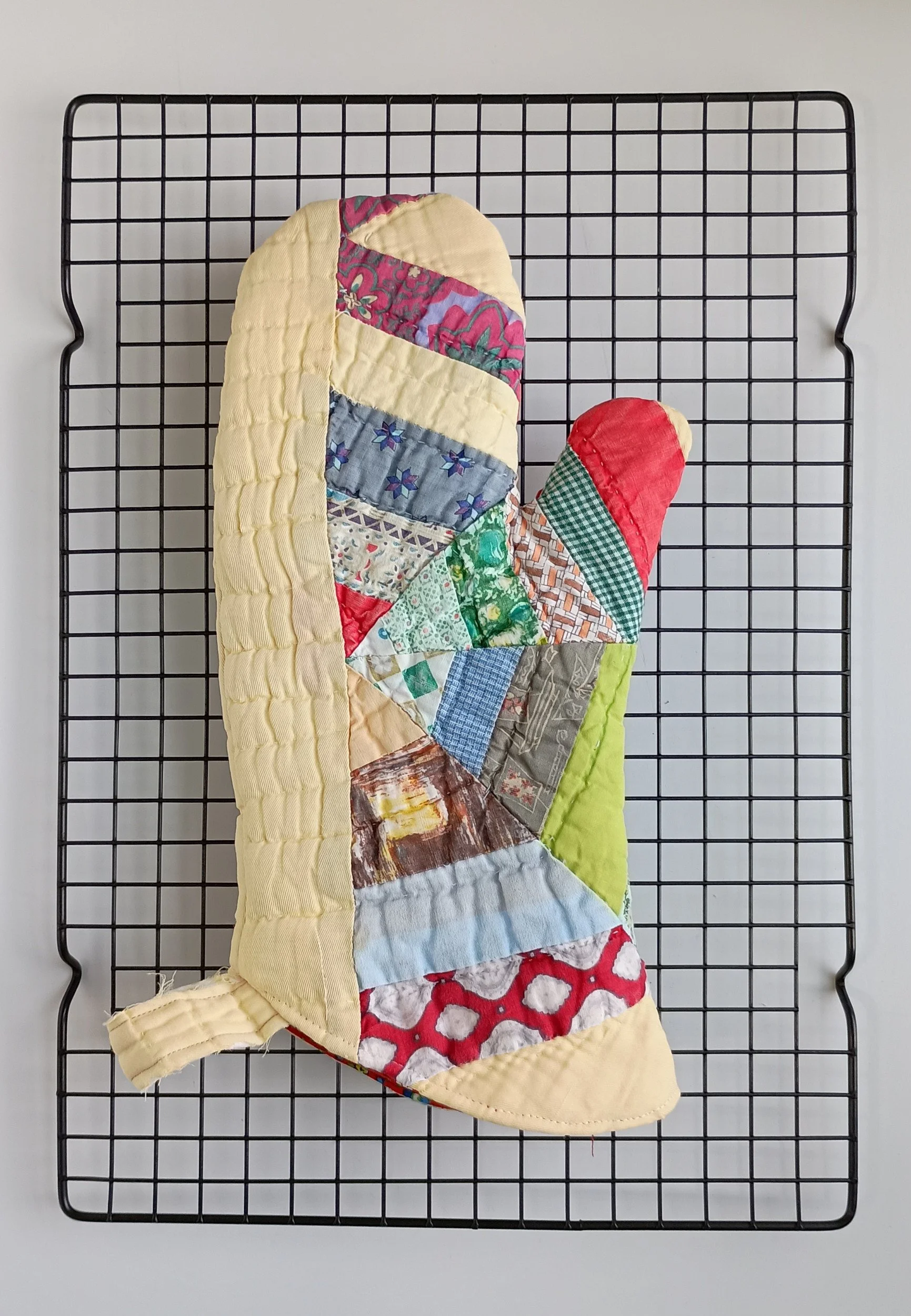 An oven mitt made from a brightly colored antique quilt