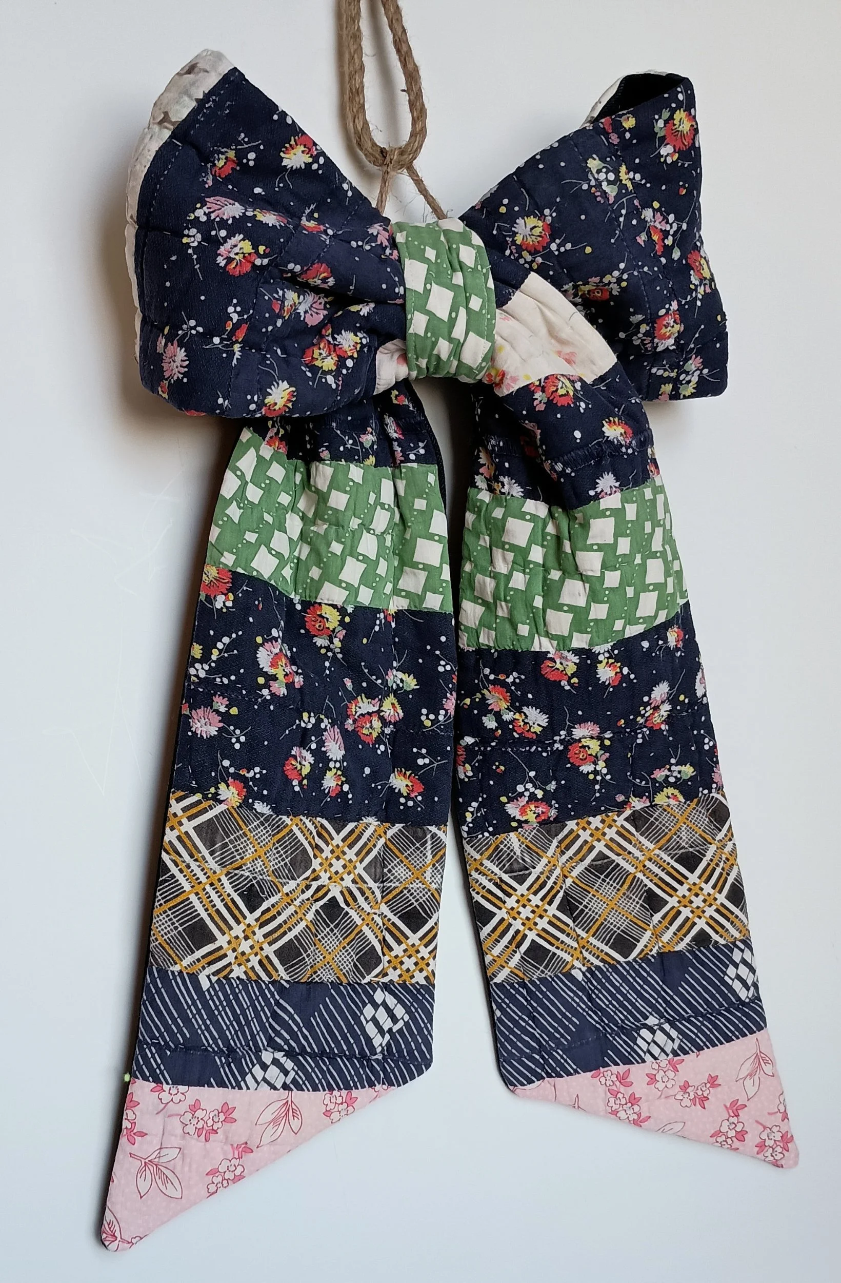 A decorative bow made from an antique patchwork, with navy being the dominant color