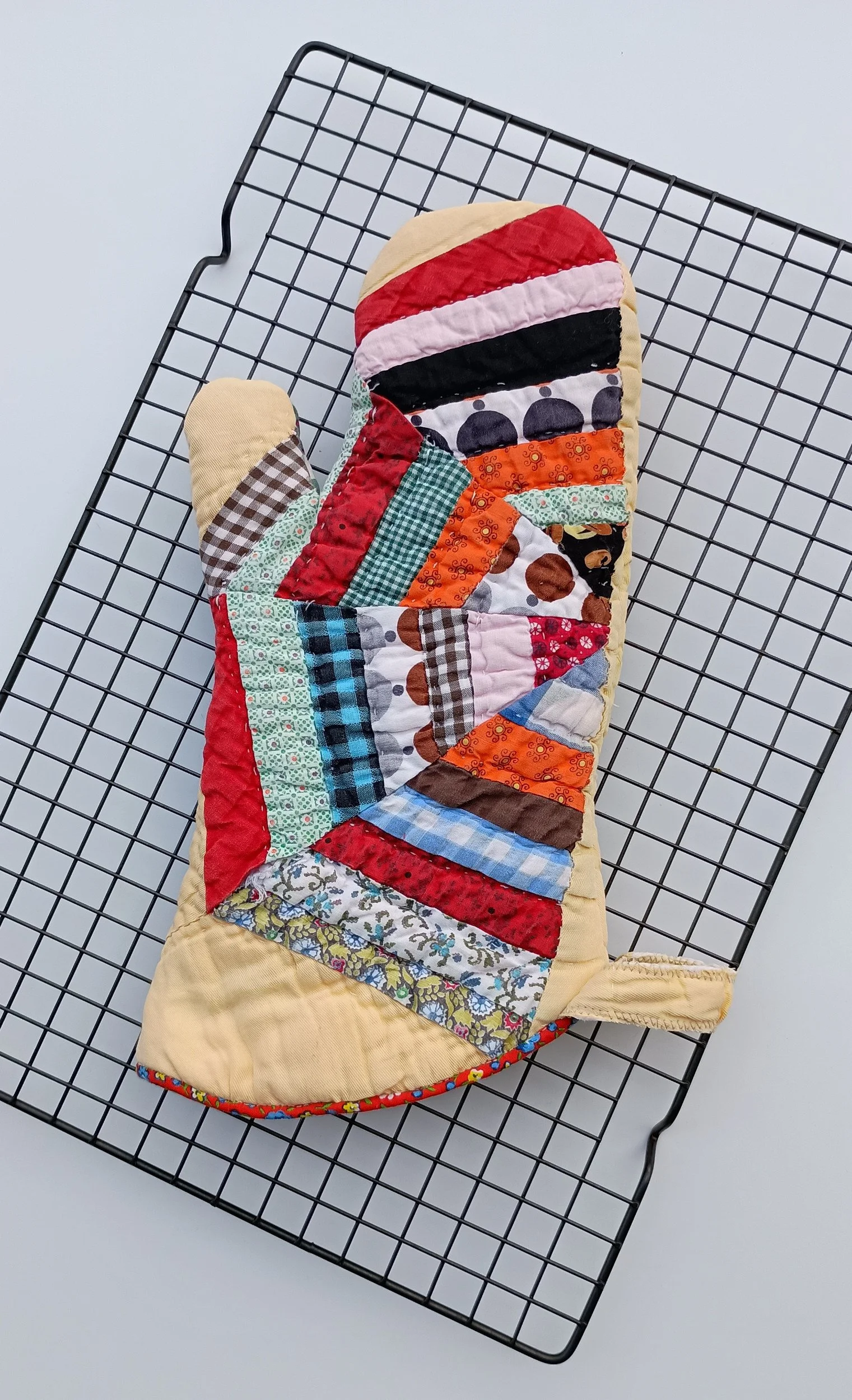 An oven mitt made from a brightly colored antique quilt