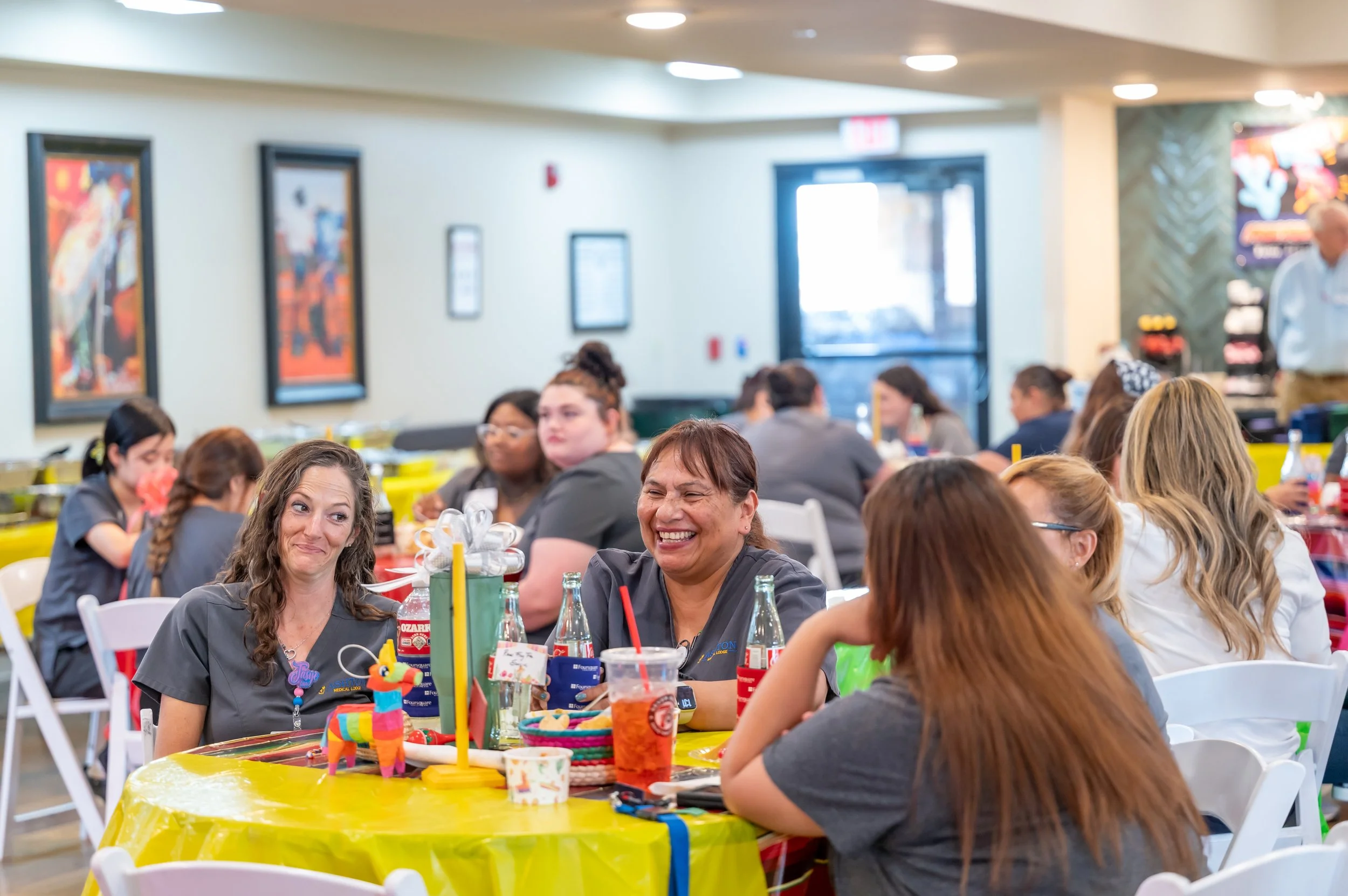 People sitting at decorated tables in a restaurant or banquet hall, celebrating, smiling, and engaging in conversation.