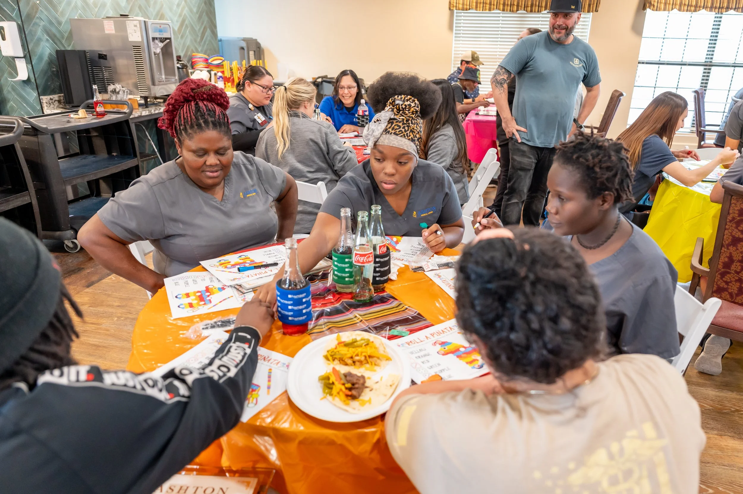 Group of people sitting around a table with drinks and Mexican food at a celebration event.