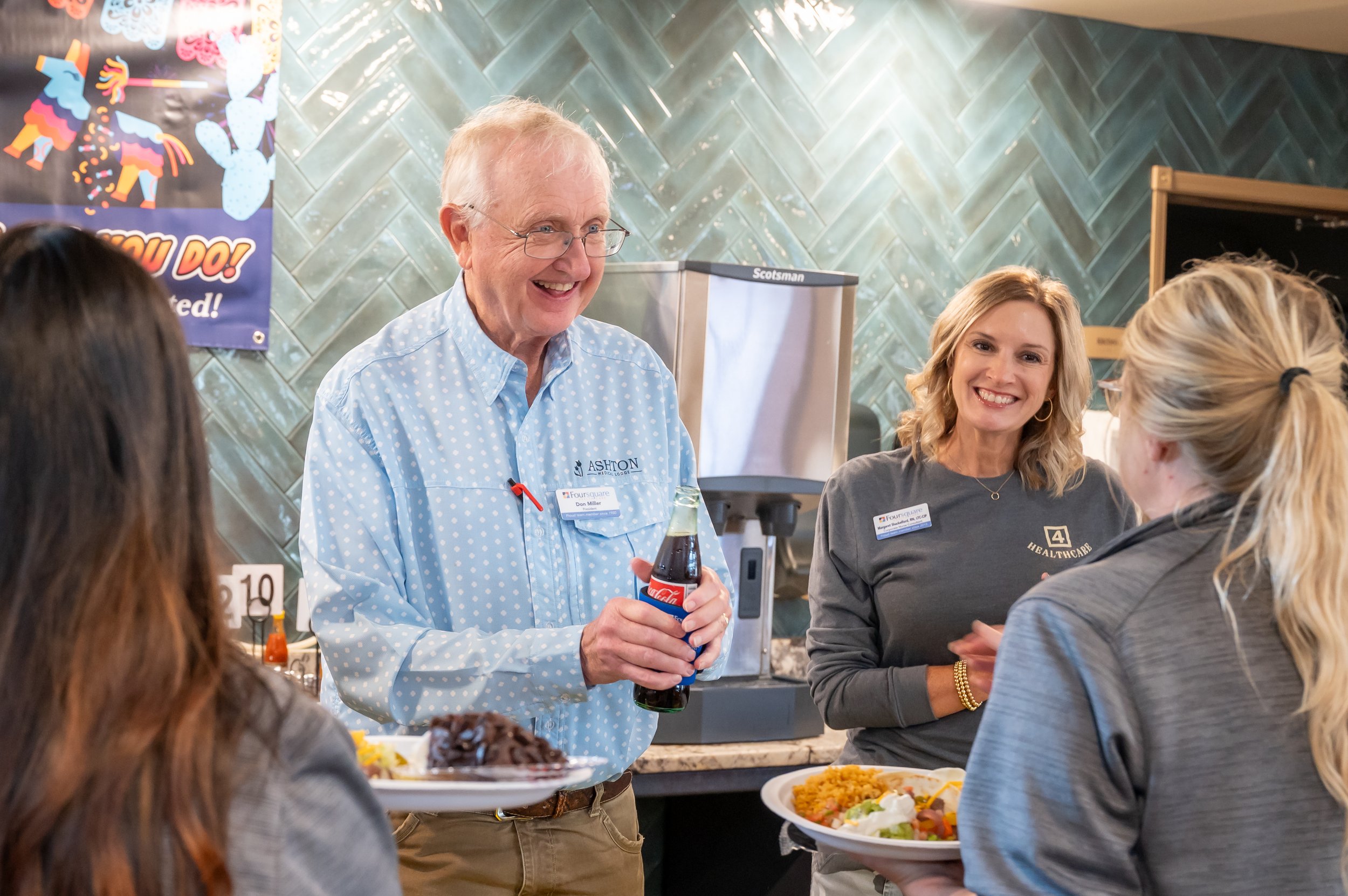 A group of people talking and smiling at a buffet table in a casual dining setting.