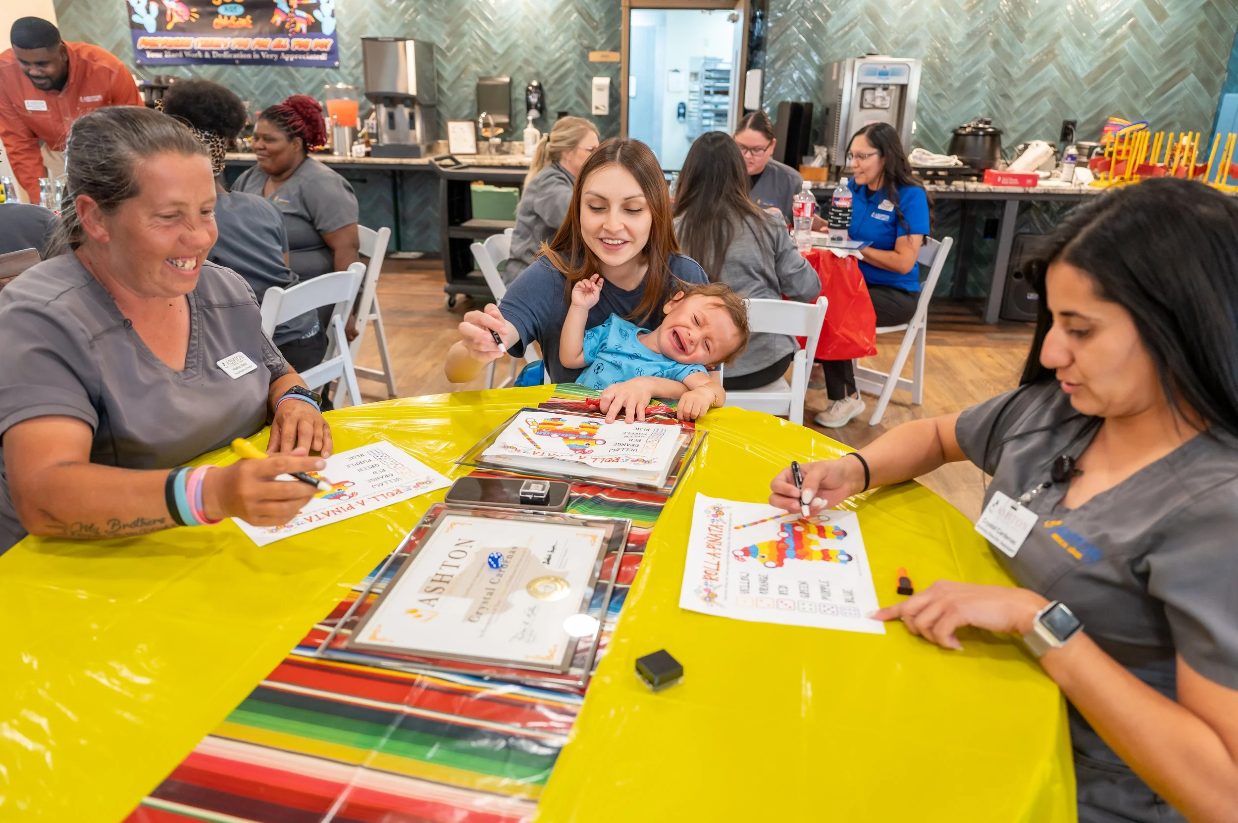 Child celebrating a birthday with family and staff at a restaurant, with decorations and coloring sheets on the table.