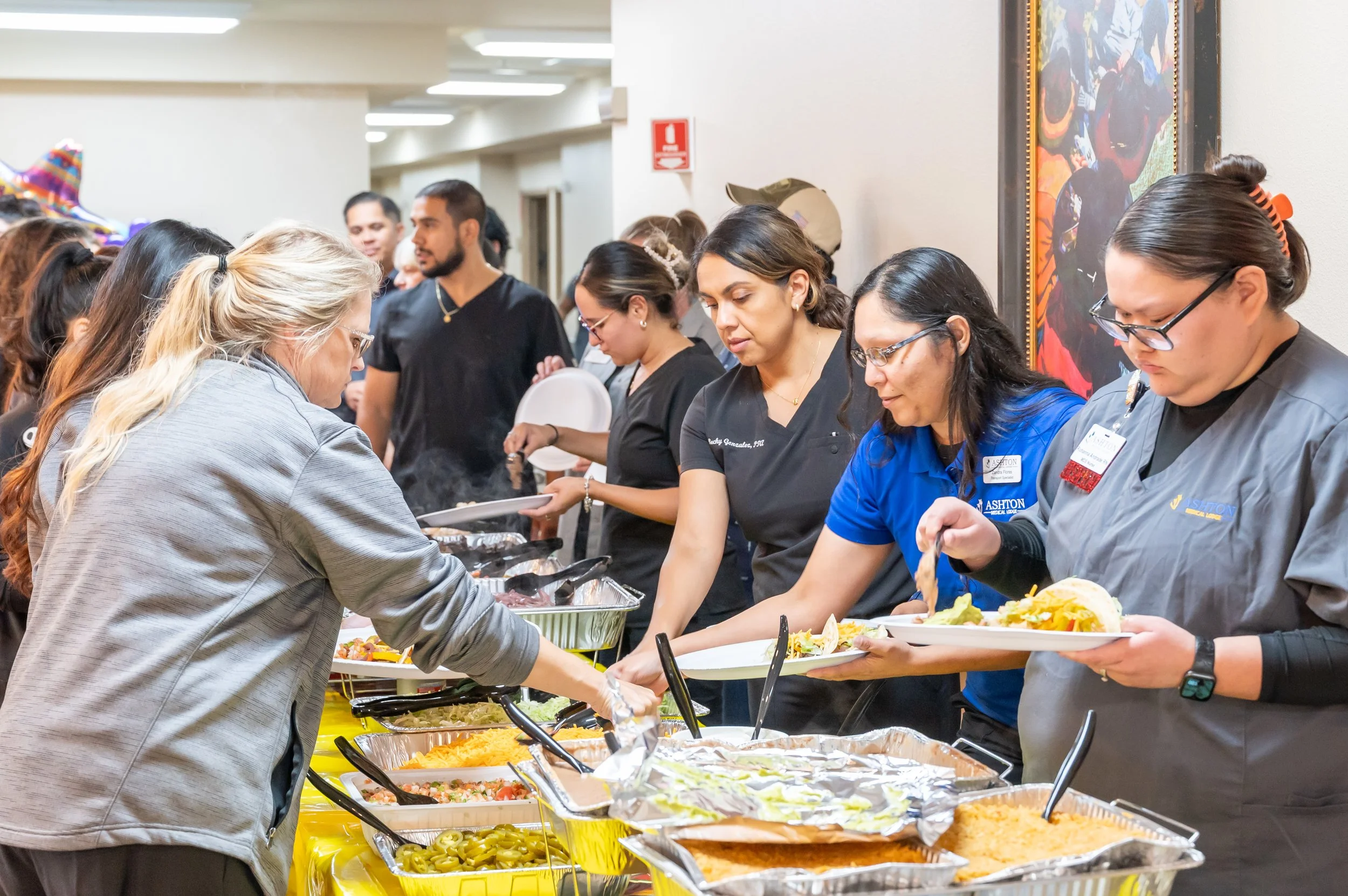 People serving themselves food at a buffet table with various dishes, at a community event or gathering.
