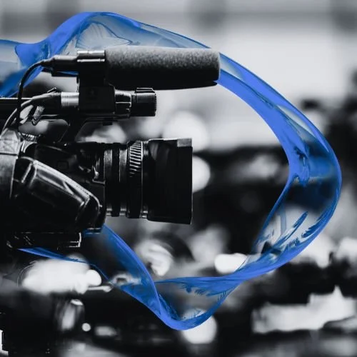 Close-up of a professional video camera with a blue film strip in front of it.