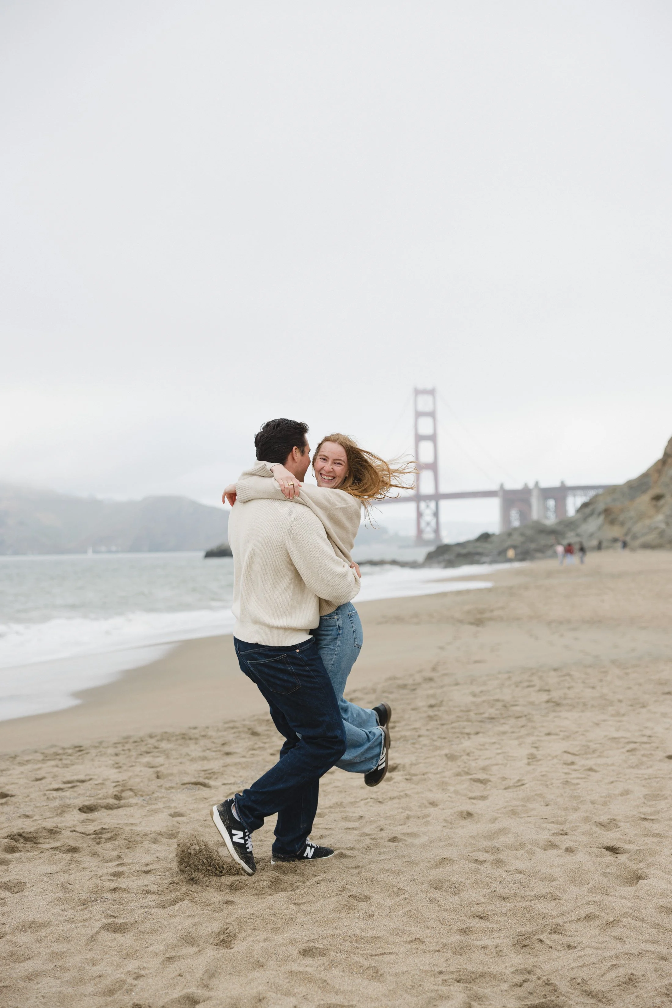ouple embracing on the beach with Golden Gate Bridge, San Francisco California wedding