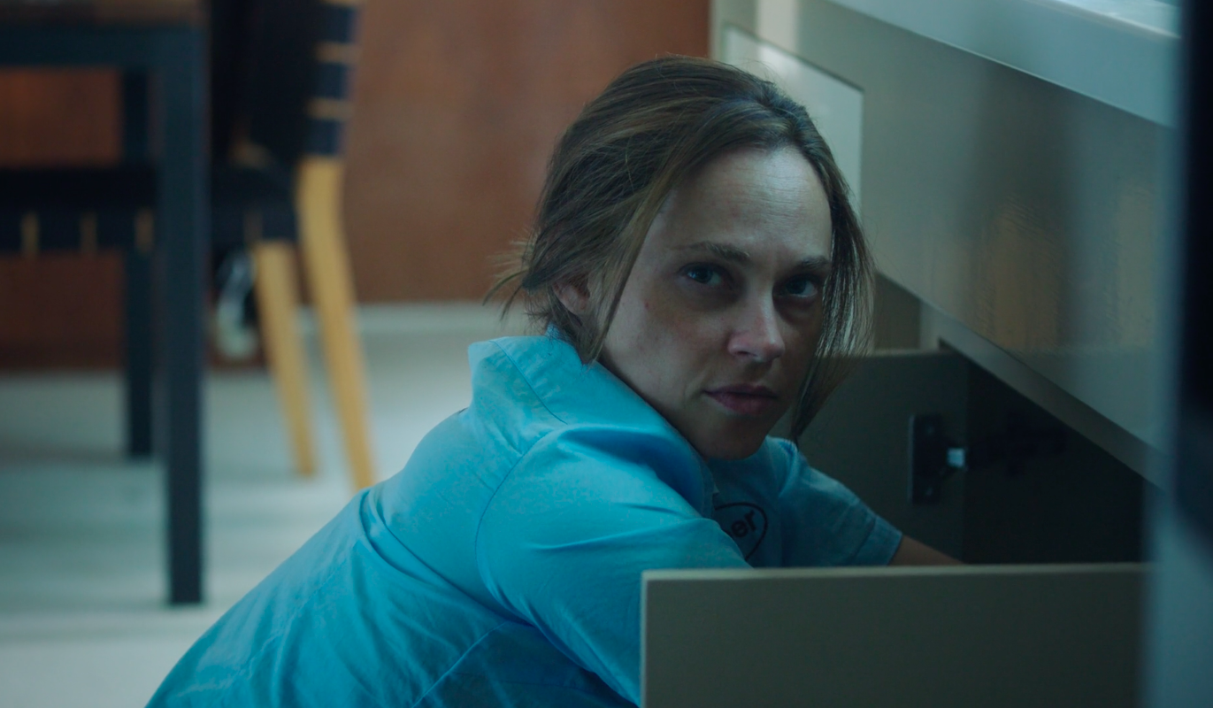 Still from the short film, EXTERMINATOR. A woman (Fiona Dourif) with unkempt hair and a slightly distressed expression wears an exterminator's uniform.