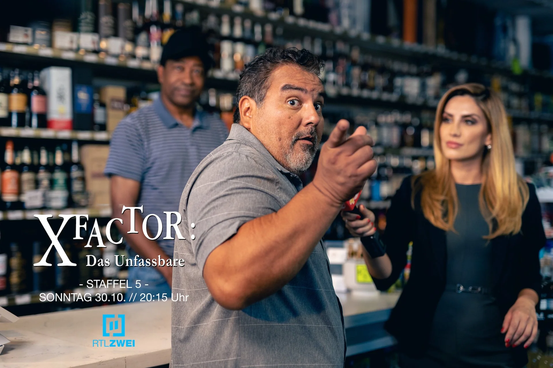 Behind-the-scenes promotional photo from the TV series X FACTOR: DAS UNFASSBARE. A female news reporter interviews a bearded man at a gas station.
