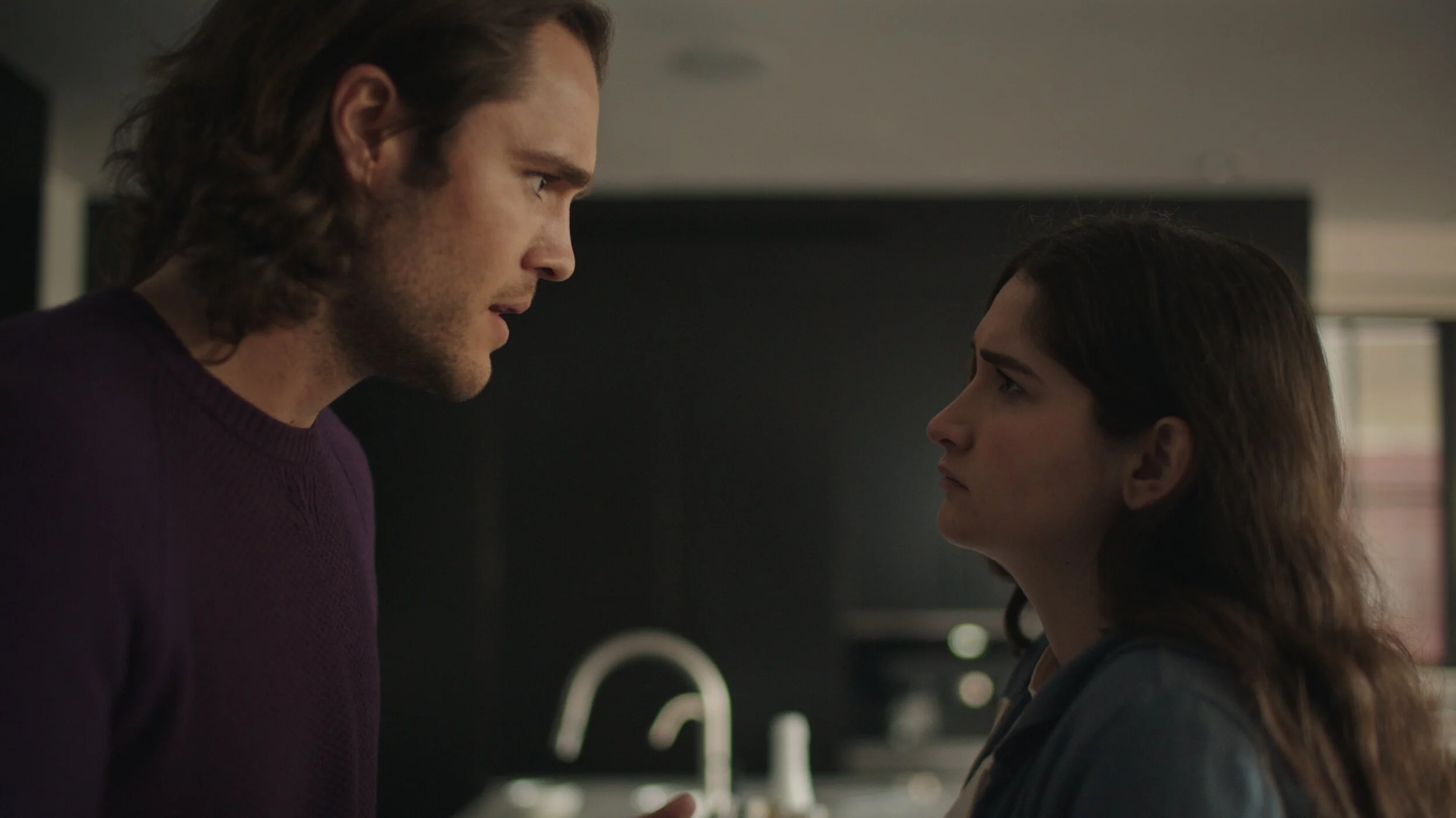 Still from the short film, FOR GOOD. A man and a woman stand close together in a tense confrontation.