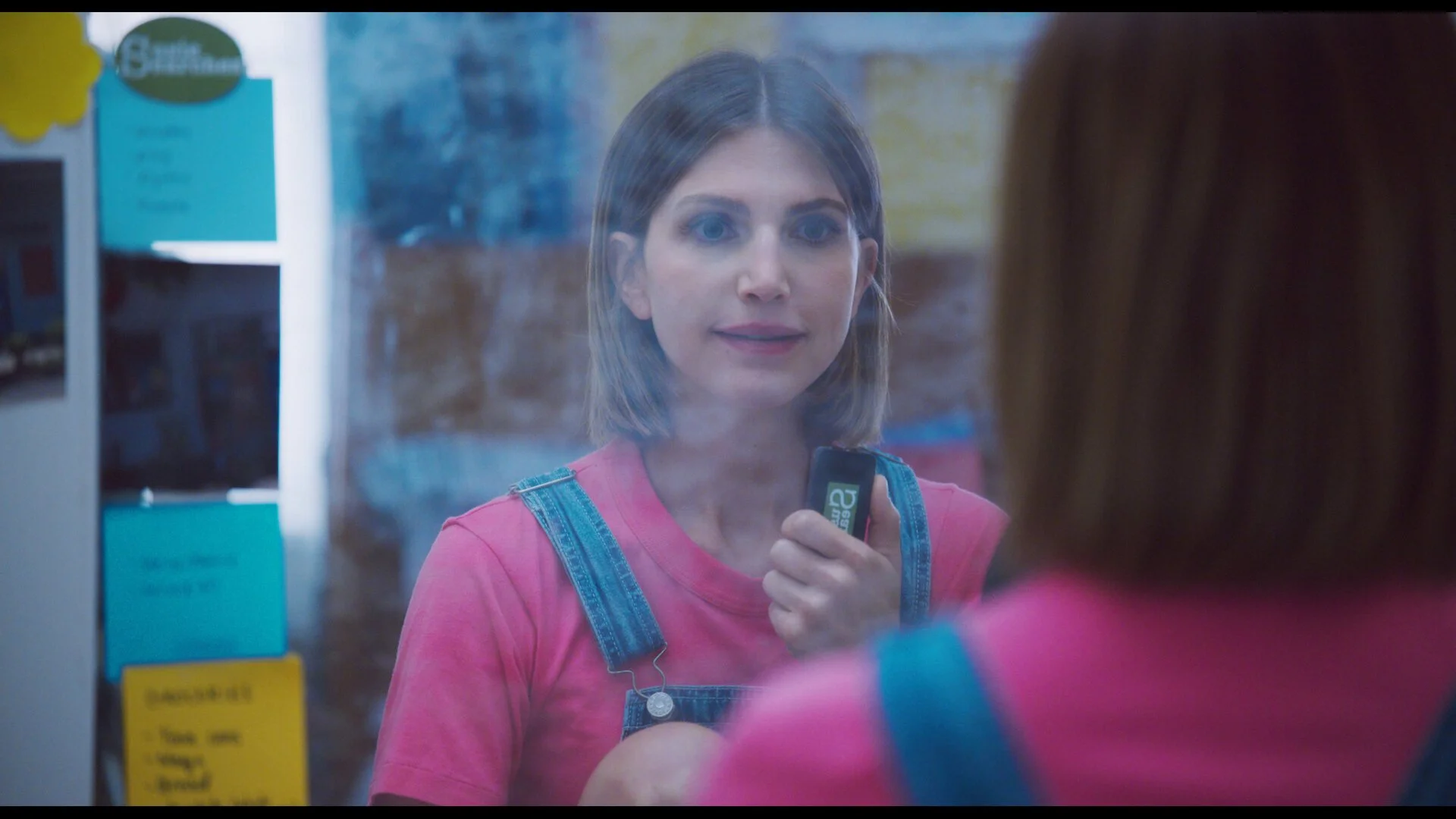Still from the short film, SUSIE SEARCHES. A young woman (Sophie Kargman) looks at herself in a mirror decorated with sticky notes.