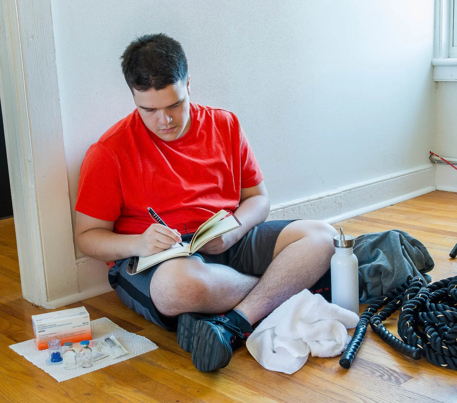 Young male octapharma WILATE patient writing in his infuse journal after exercise with a battle rope