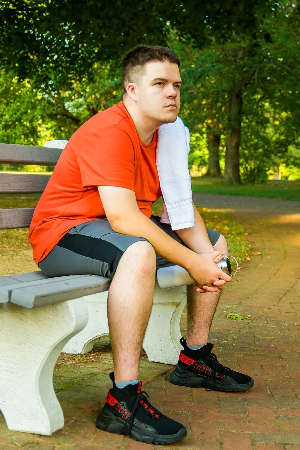 Young male octapharma WILATE patient resting after exercise on a park bench on a sunny day