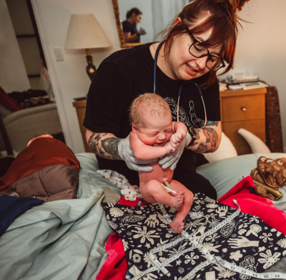 Homebirth midwife in Logan, Utah holding a newborn baby during a newborn exam