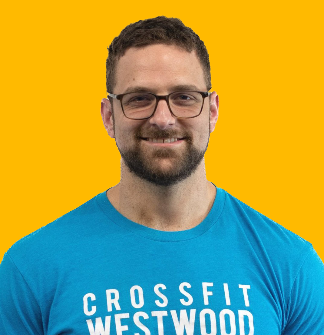 A smiling man with glasses and a beard, wearing a blue T-shirt that says "Crossfit Westwood," against a yellow background.