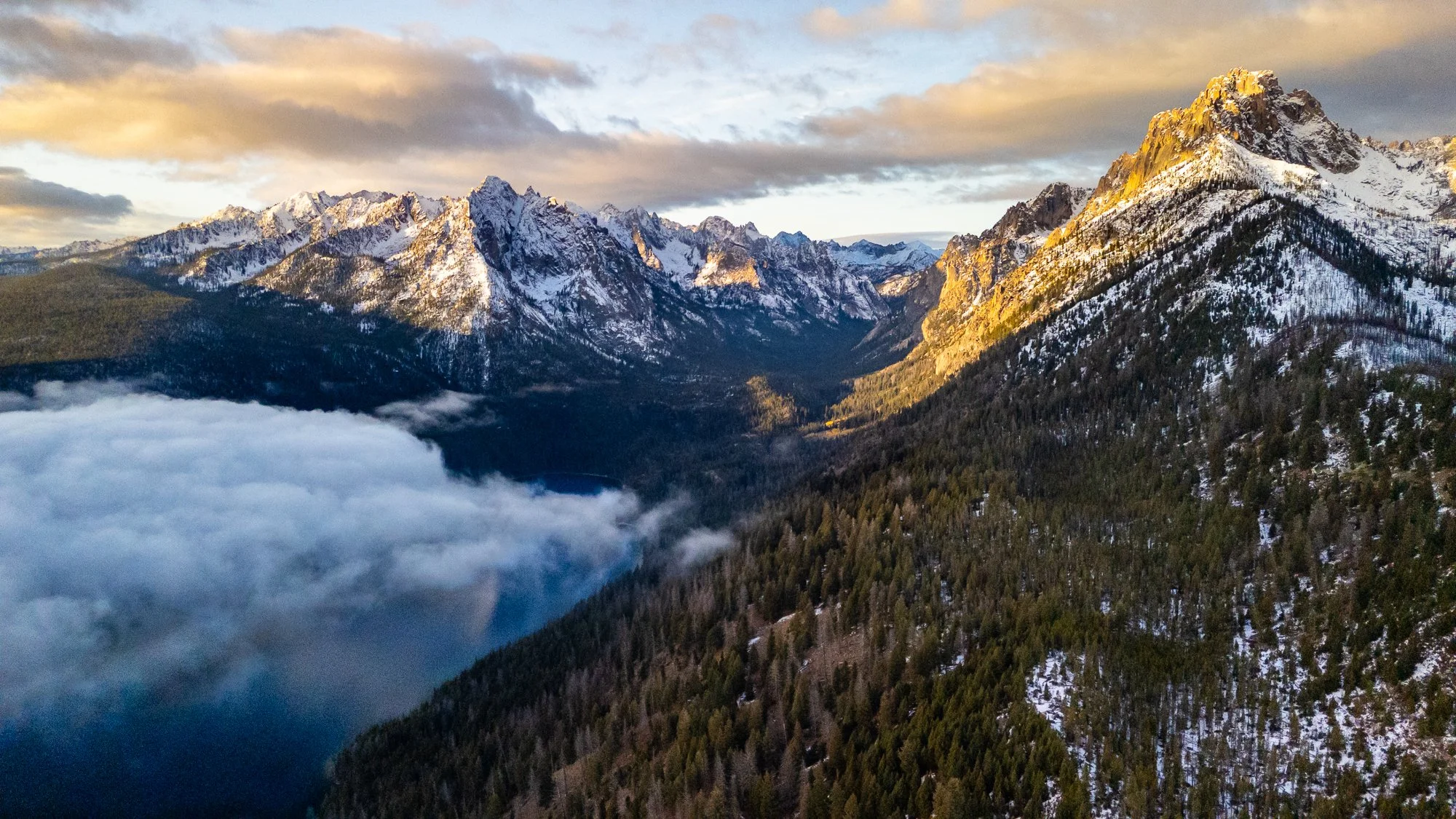 Drone aerial photograph of the Sawtooth Mountains and alpine lake near Stanley, Idaho at sunrise, captured by Jon Conti Visuals.