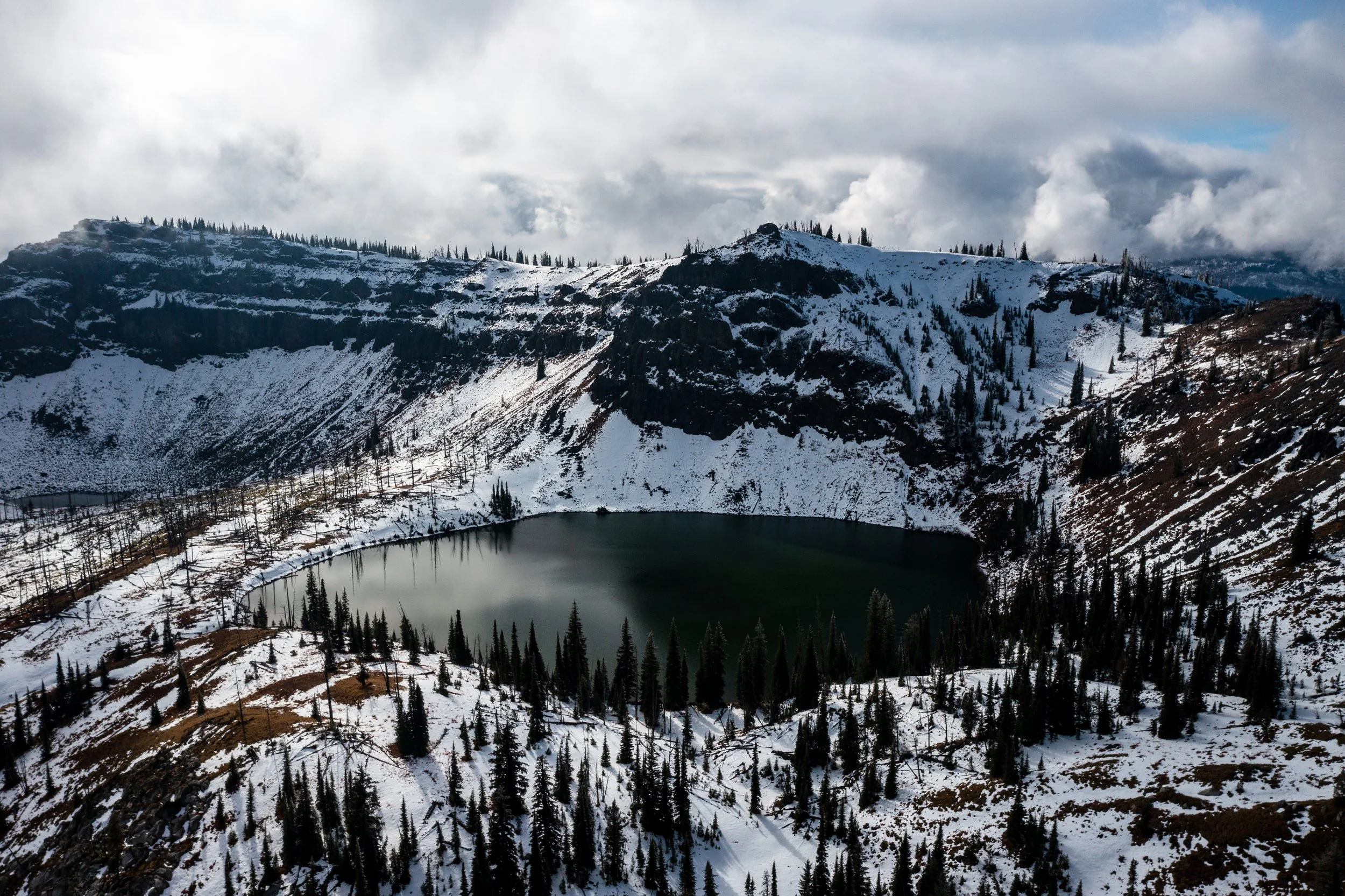 Aerial drone photograph of Hard Butte Lake near McCall, Idaho, captured by Jon Conti Visuals. This 5K winter image shows the frozen lake surrounded by snow-covered forest and mountain ridges — a quiet, cinematic view of Idaho’s Payette National Fores