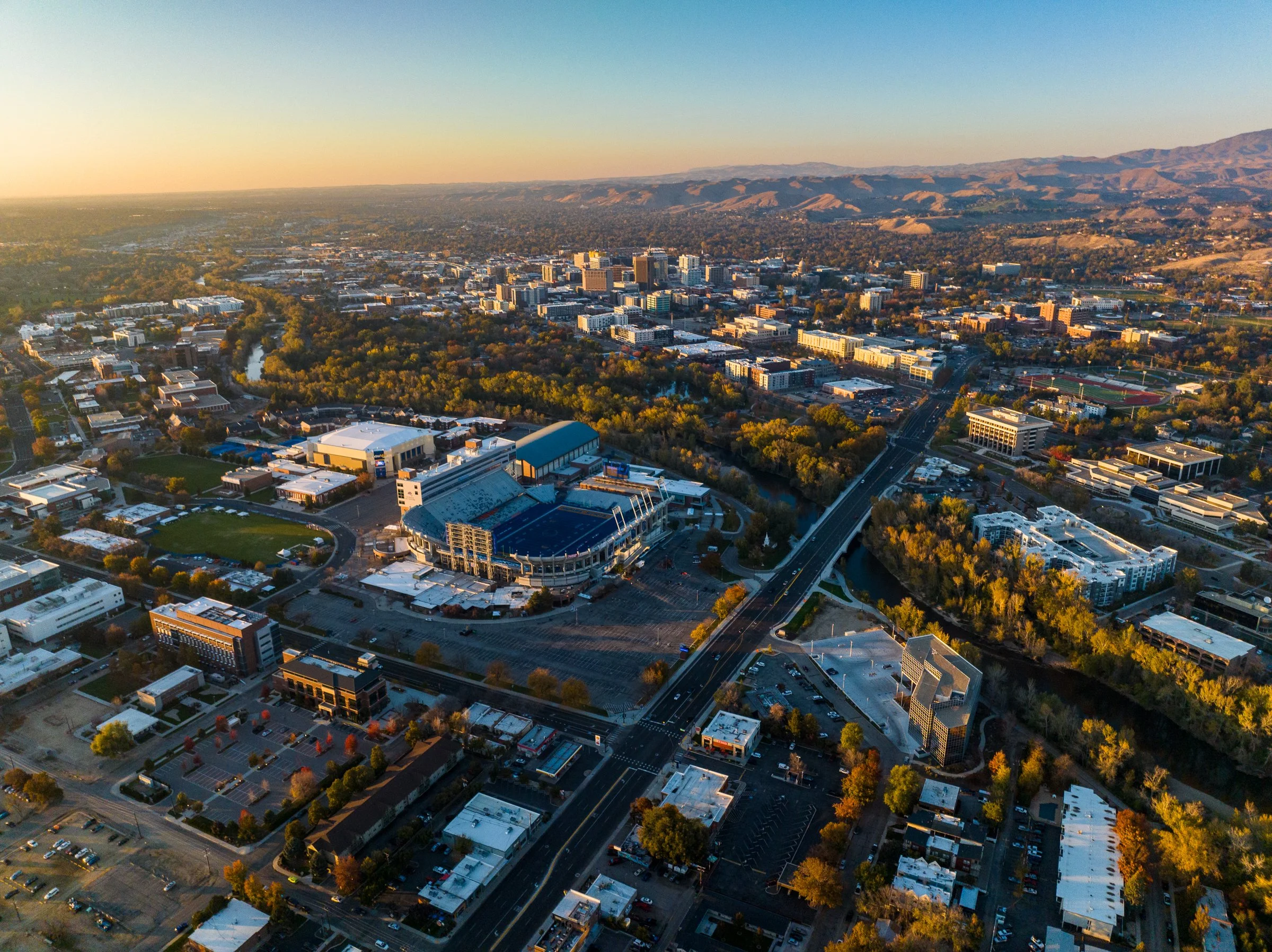 Aerial drone photo of Boise, Idaho at sunset with Boise State football stadium in the foreground and downtown skyline in the background.