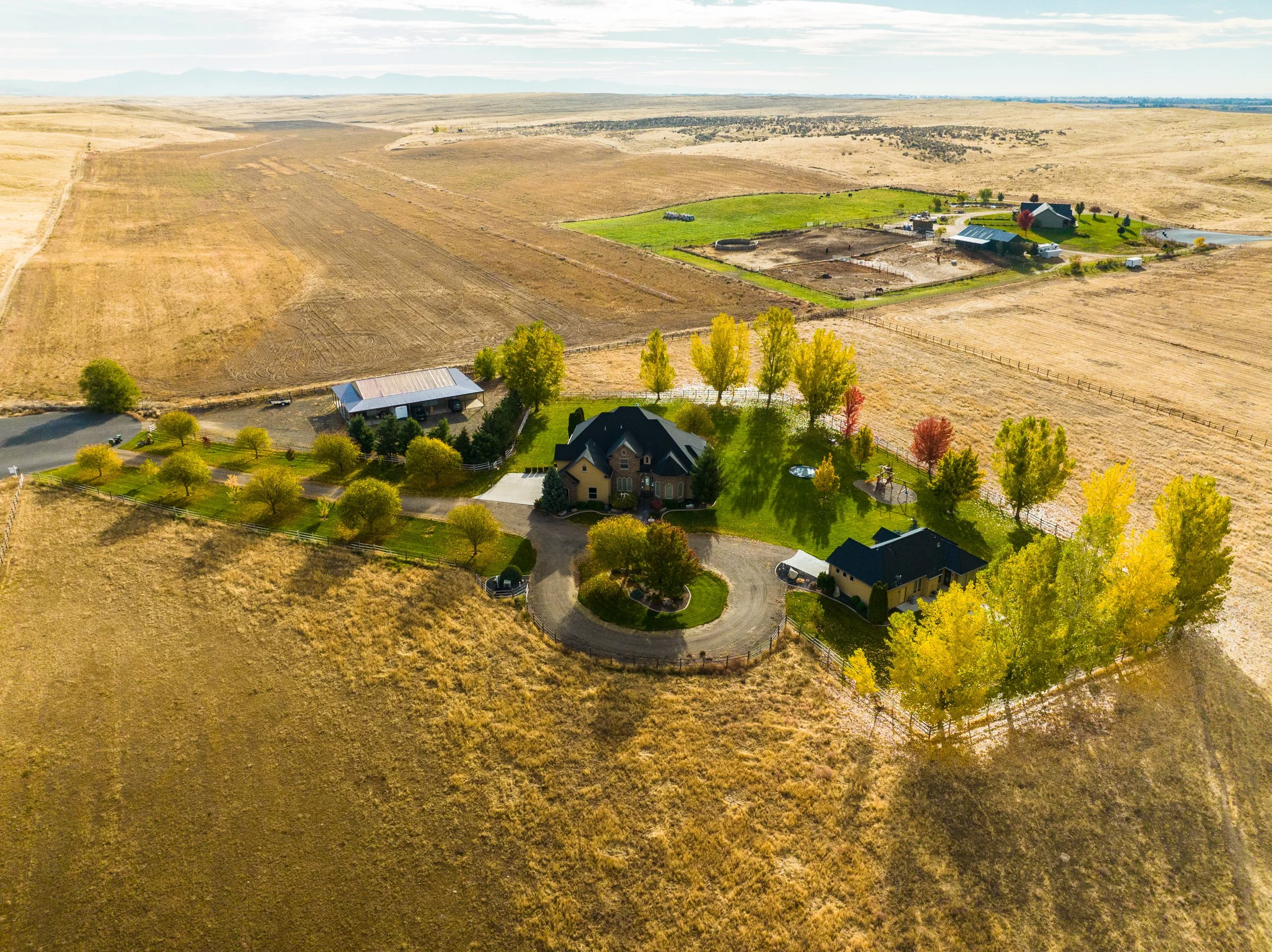 Aerial drone photo of a luxury home property in Caldwell, Idaho, showing landscaped grounds and surrounding farmland.